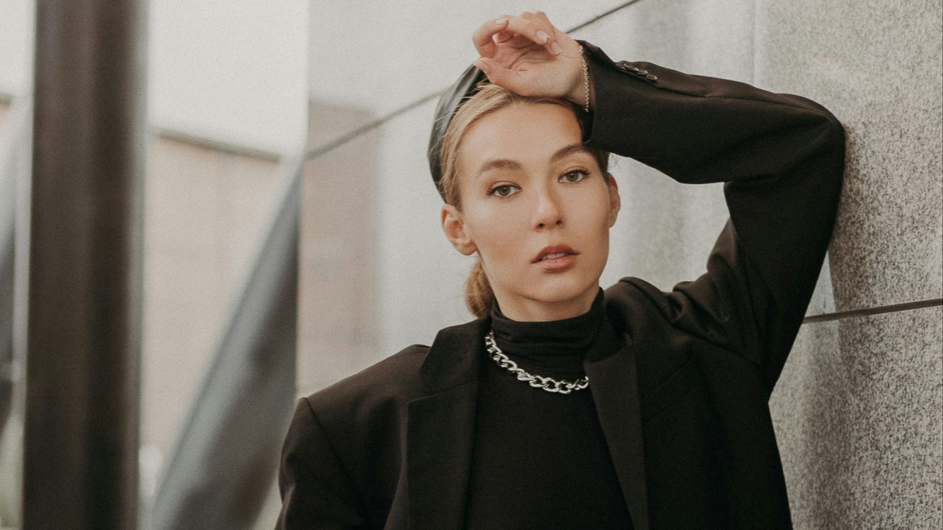 woman in black coat standing near gray concrete wall during daytime