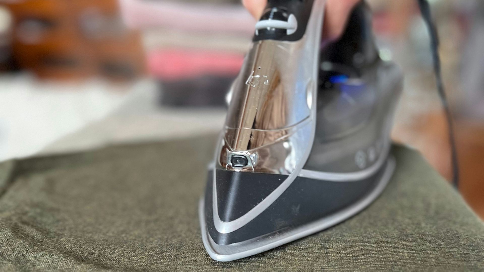 A person ironing a green shirt with a black iron