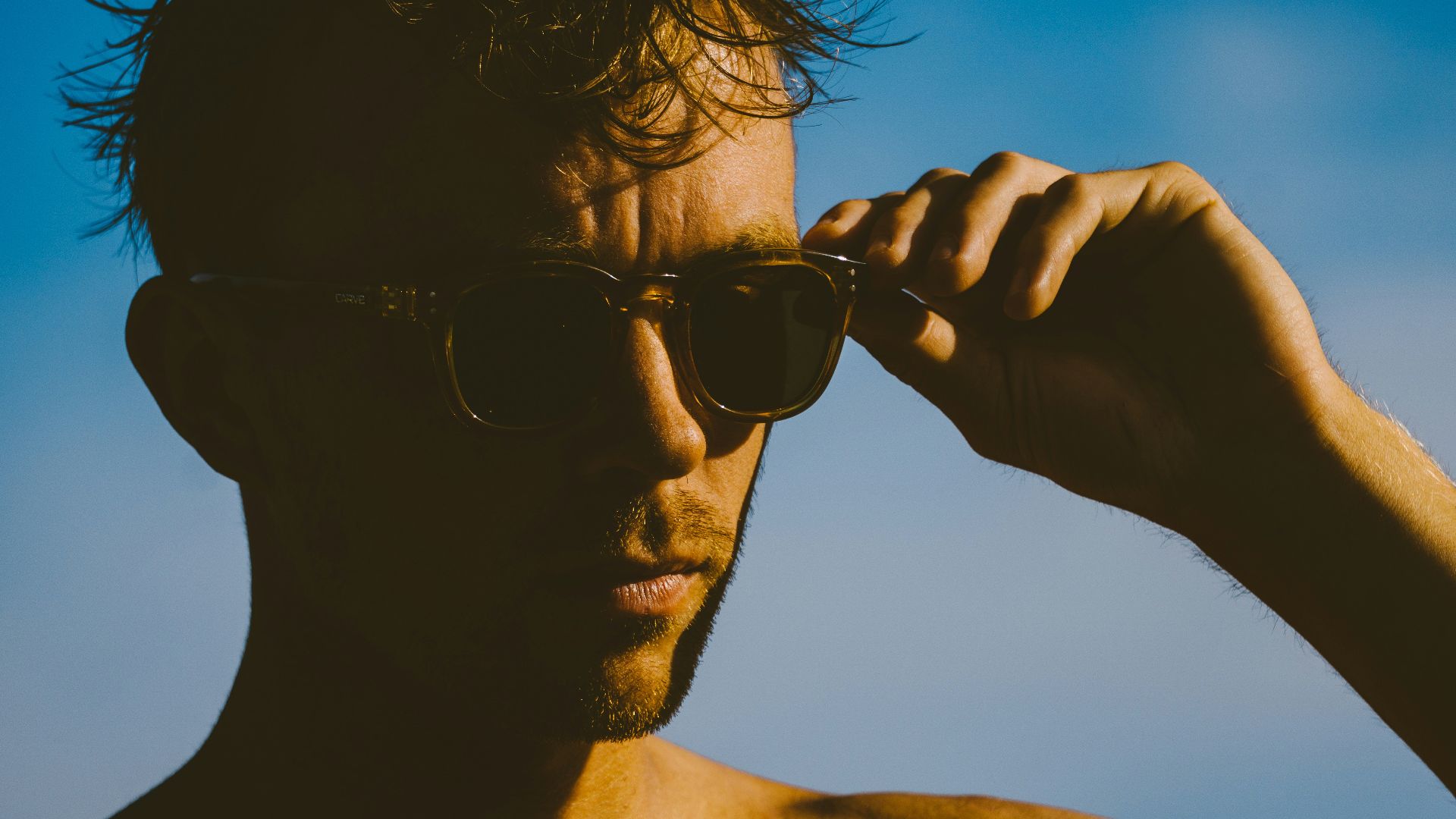 man wearing black sunglasses holding black smartphone during daytime