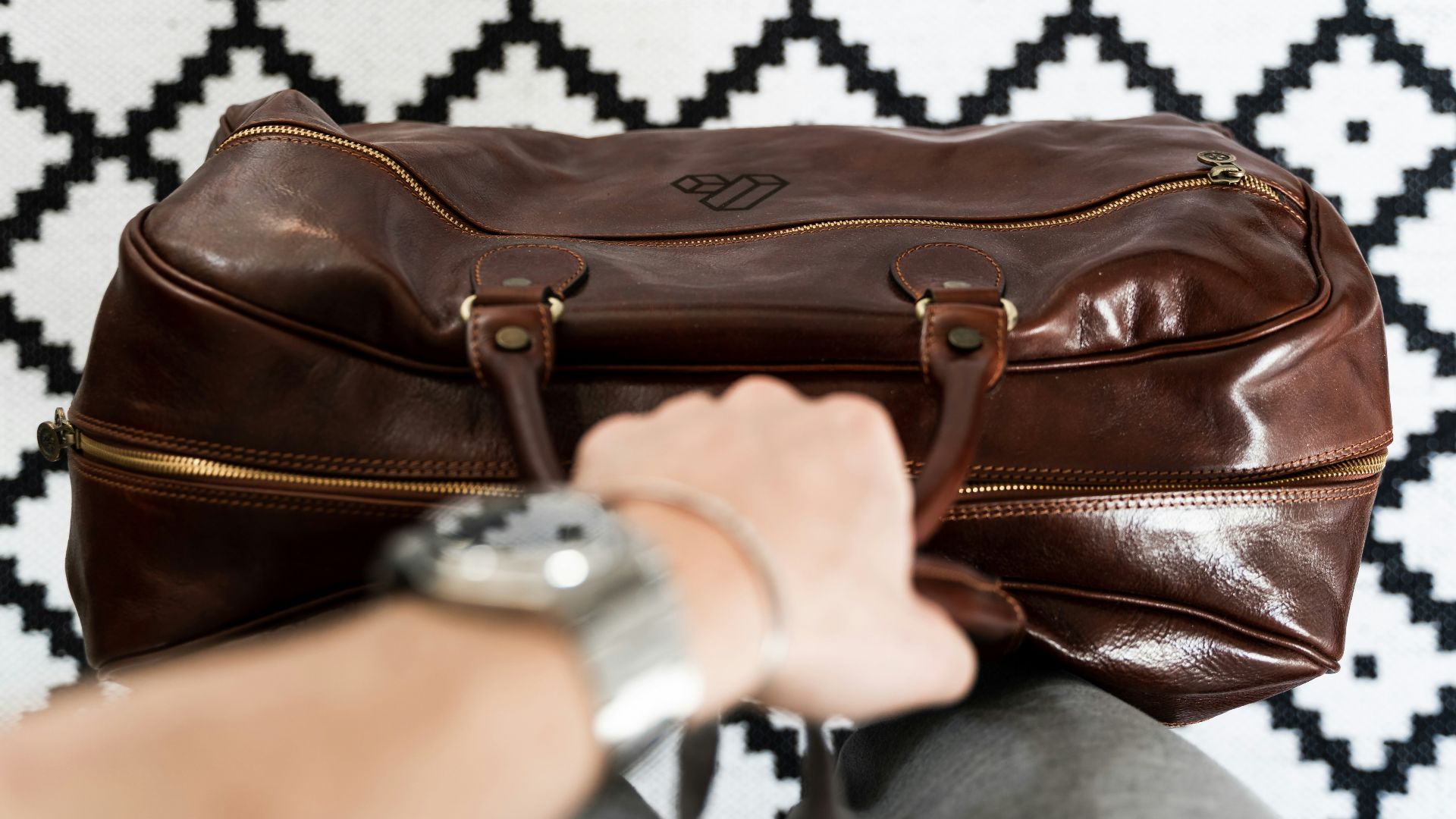 a person is holding a brown leather bag