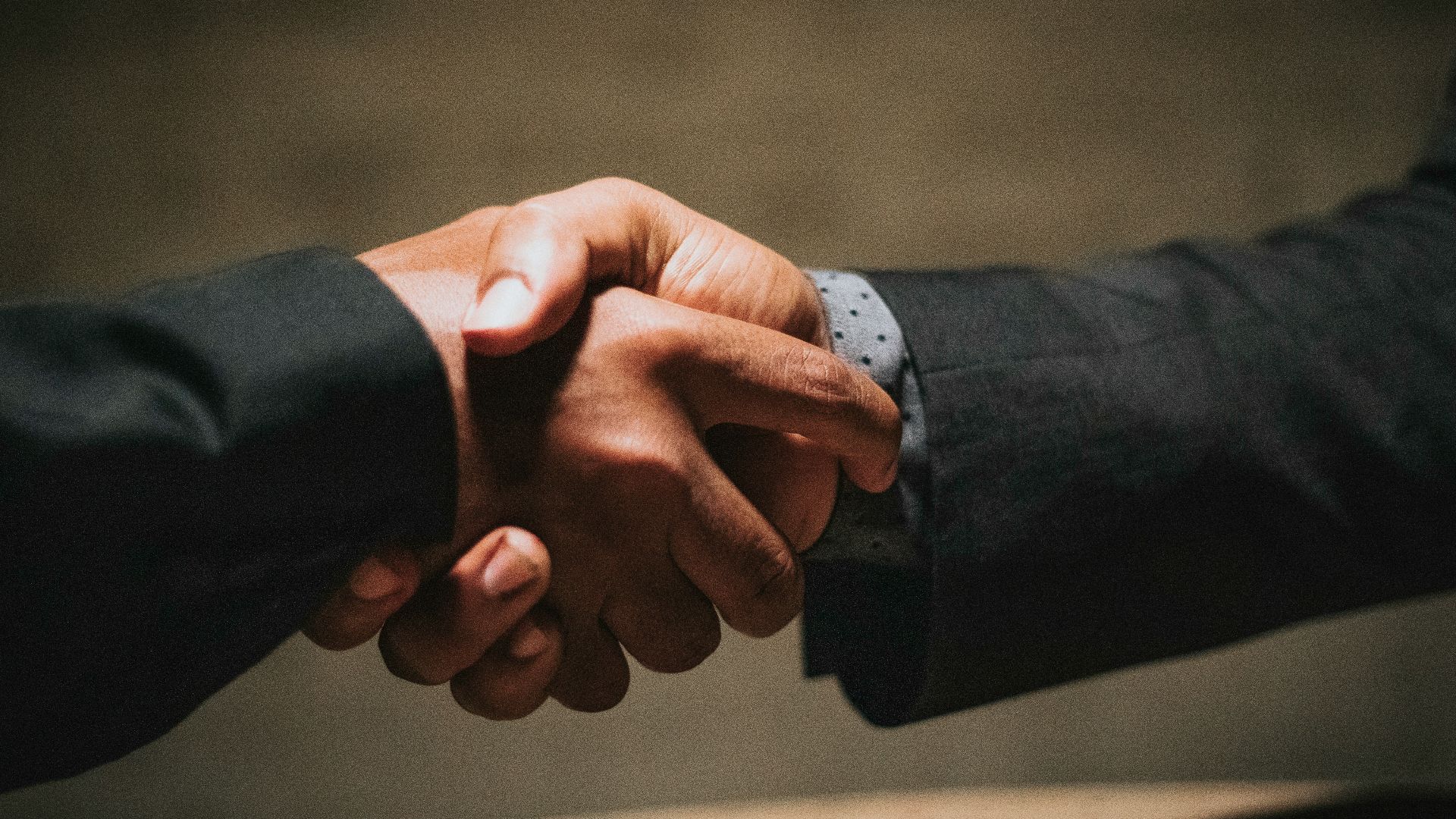 two people shaking hands over a wooden table