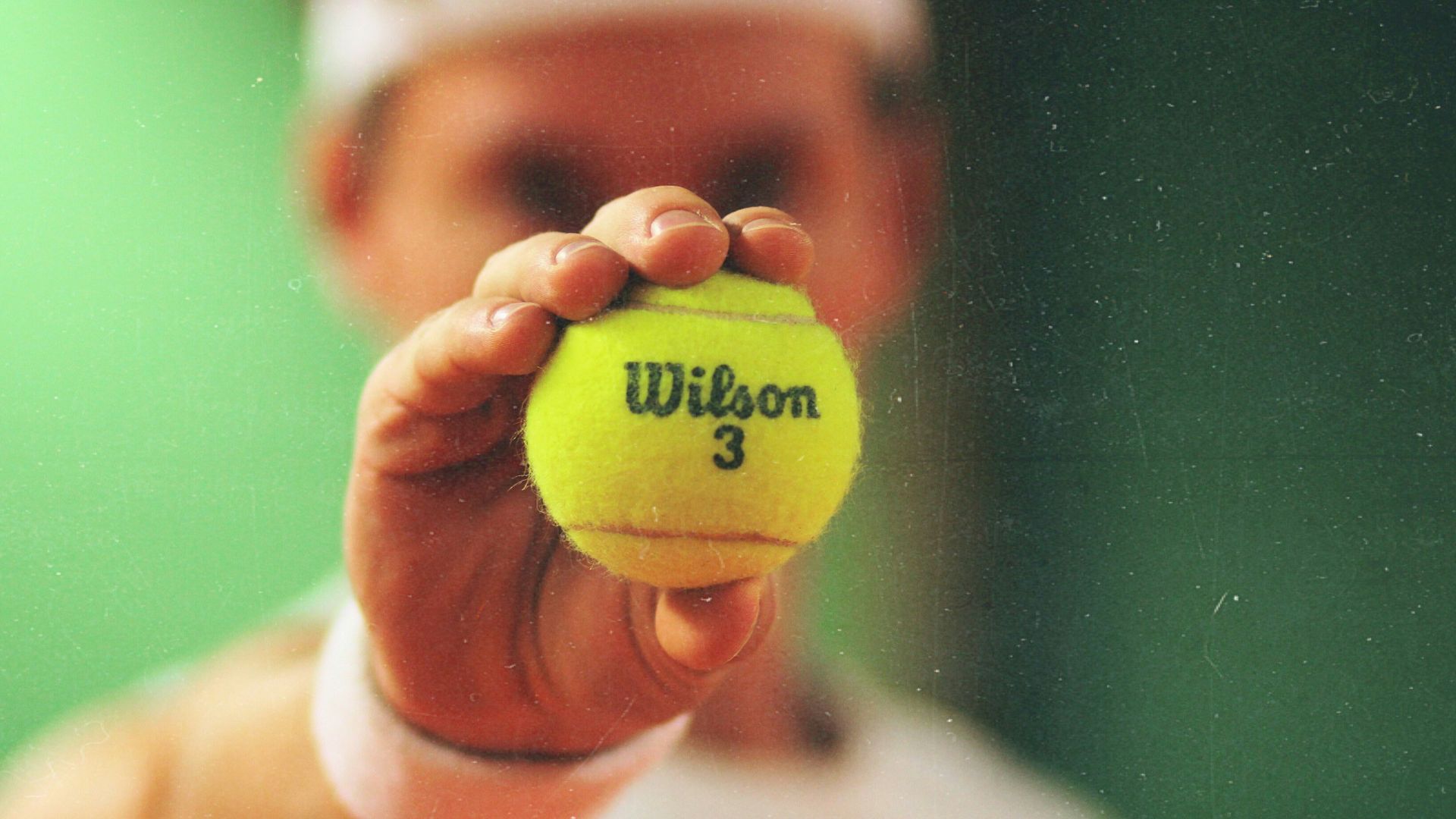 person holding green Wilson tennis ball