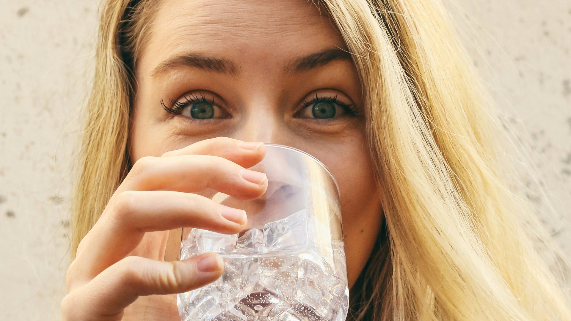 woman in white crew neck shirt drinking water