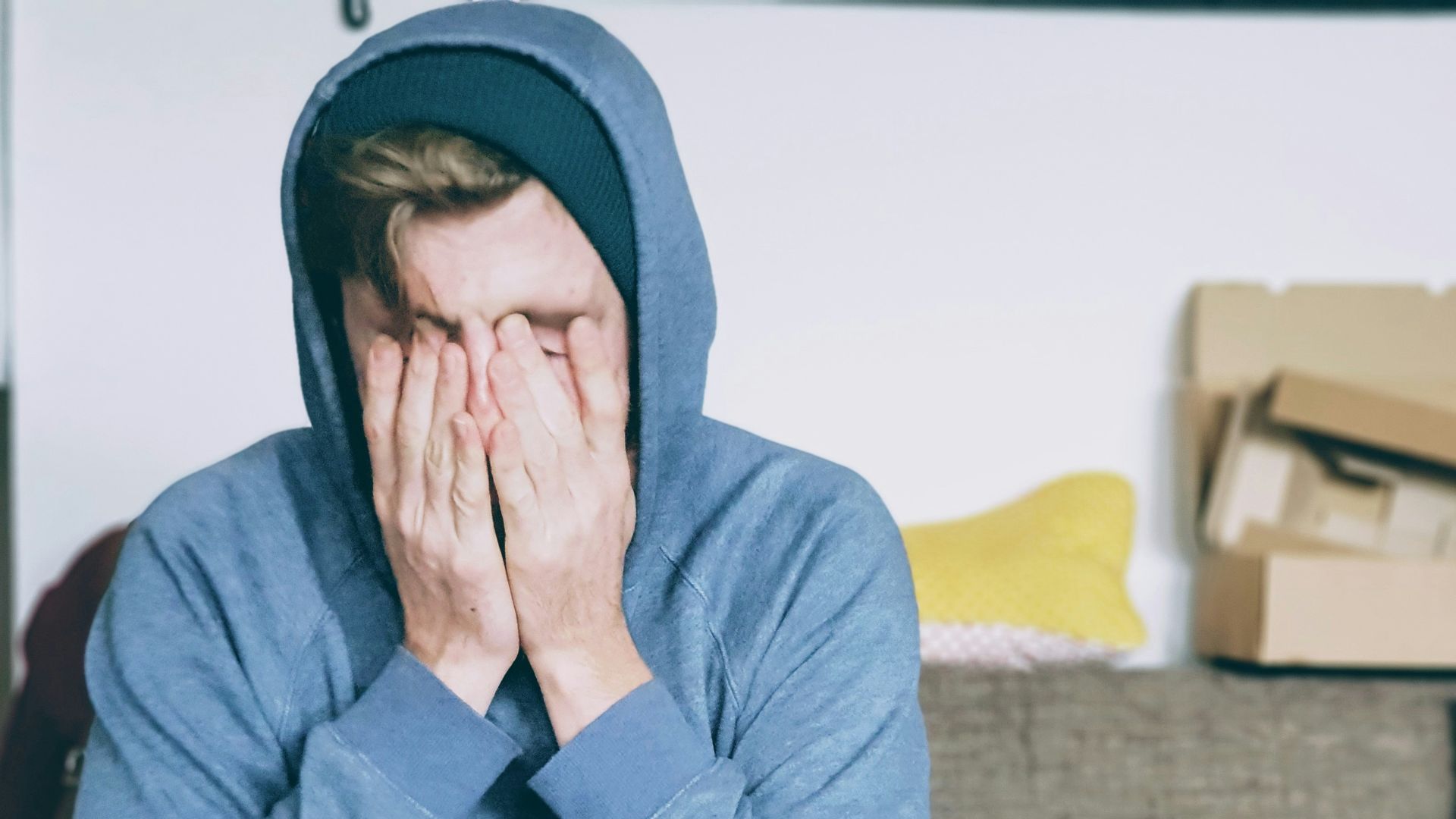 man covering face with both hands while sitting on bench