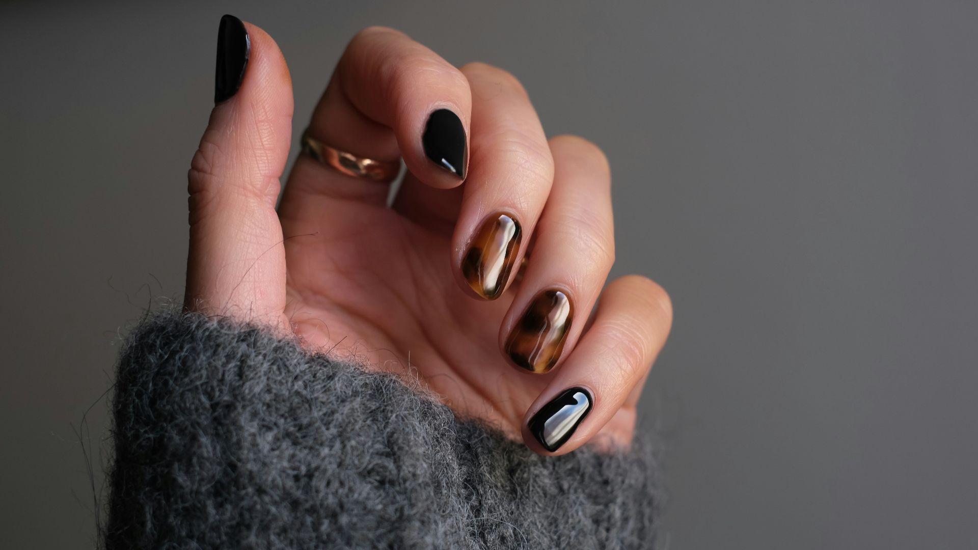 person wearing silver ring with black manicure