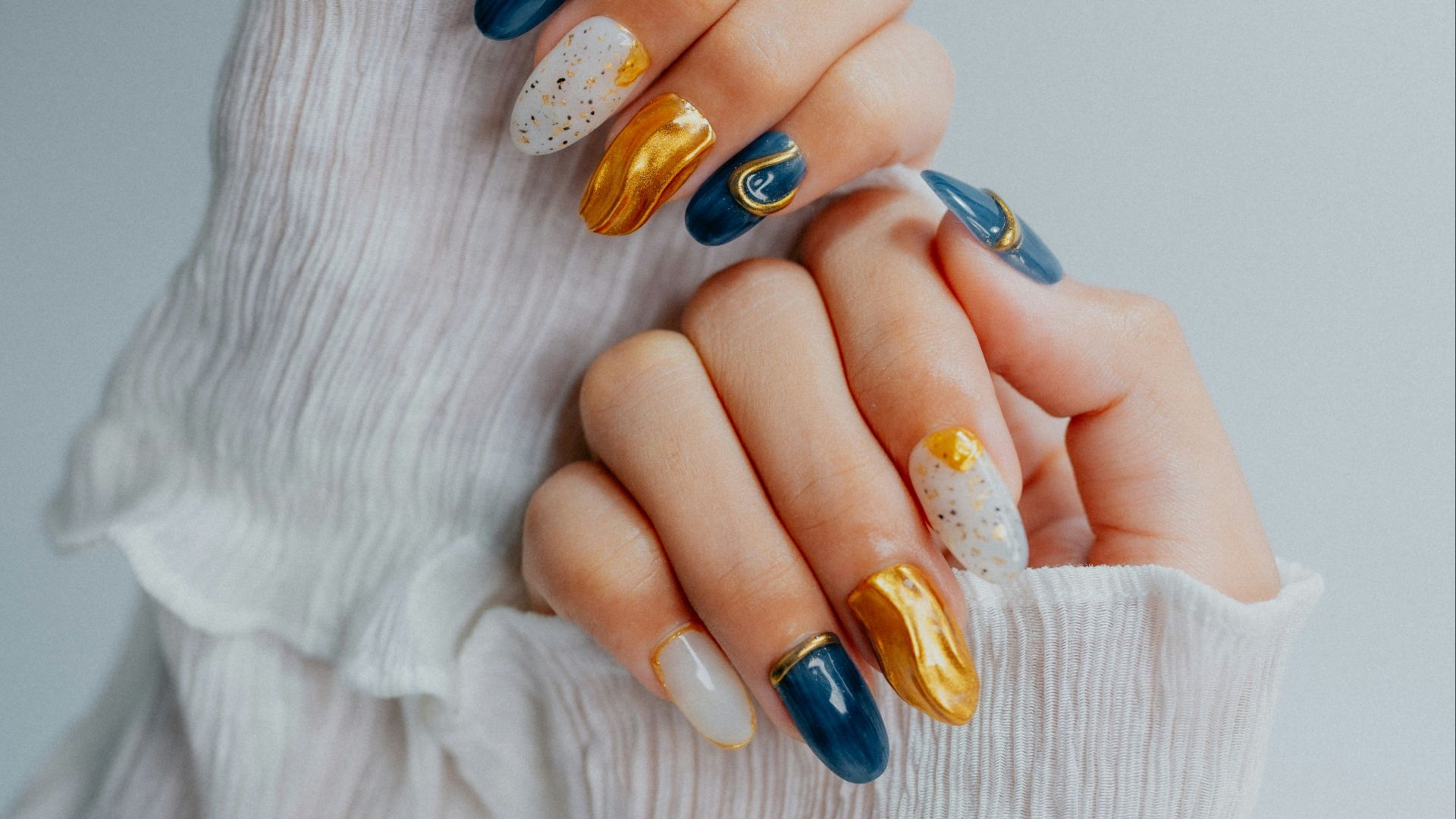 Woman's hands with ornate navy, gold, and white nails