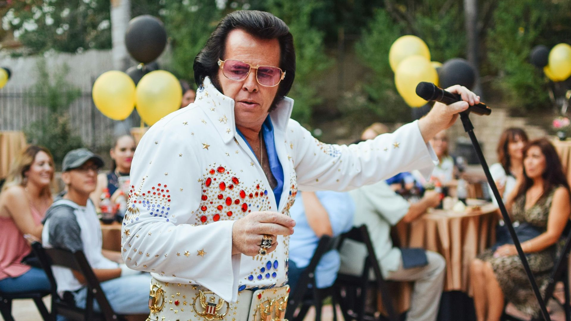 a man dressed in elvis clothing holding a microphone