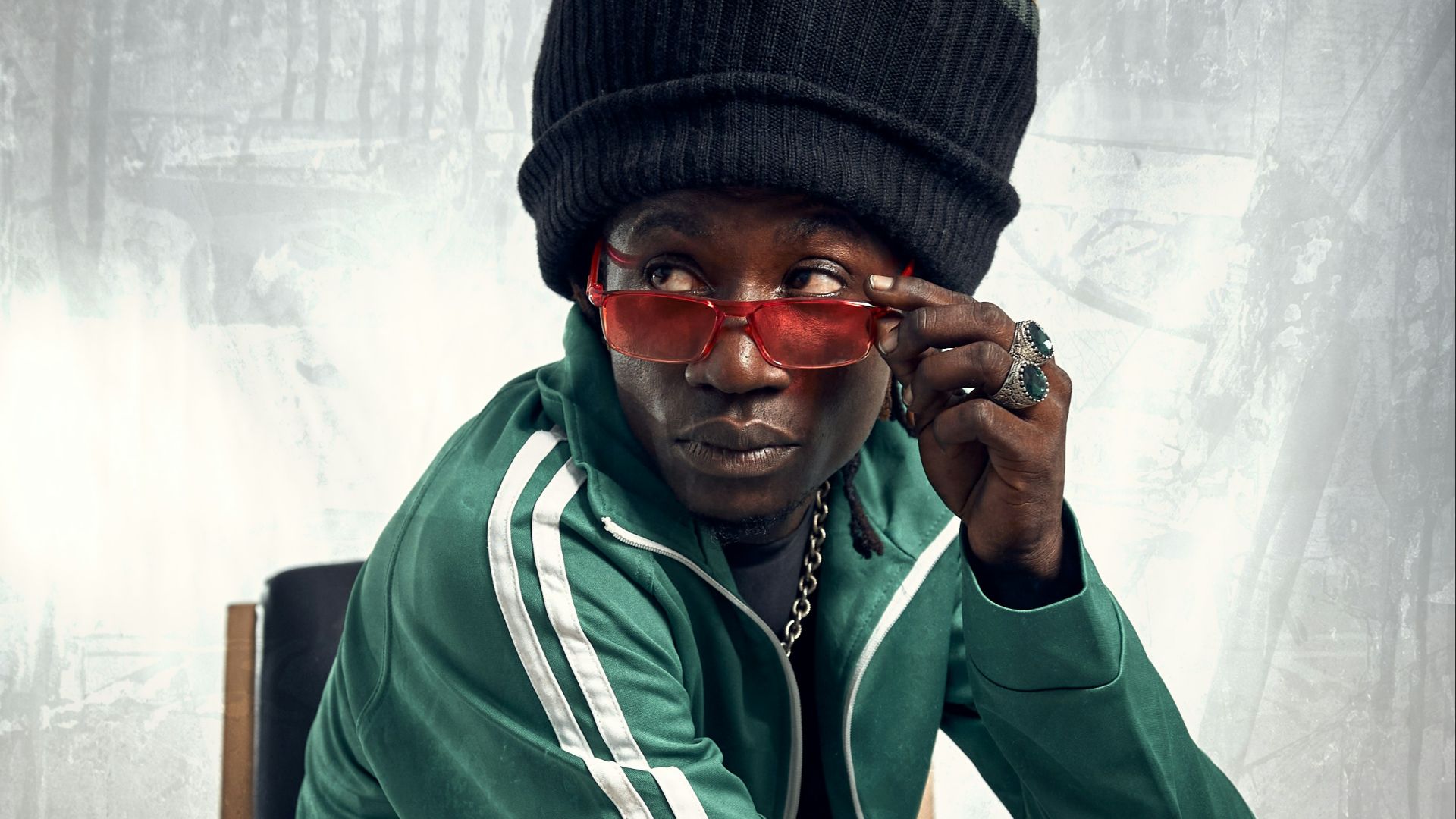 A man sitting on a chair wearing a hat and sunglasses