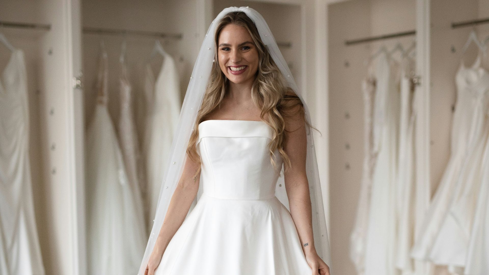 a woman in a wedding dress standing in front of a rack of dresses