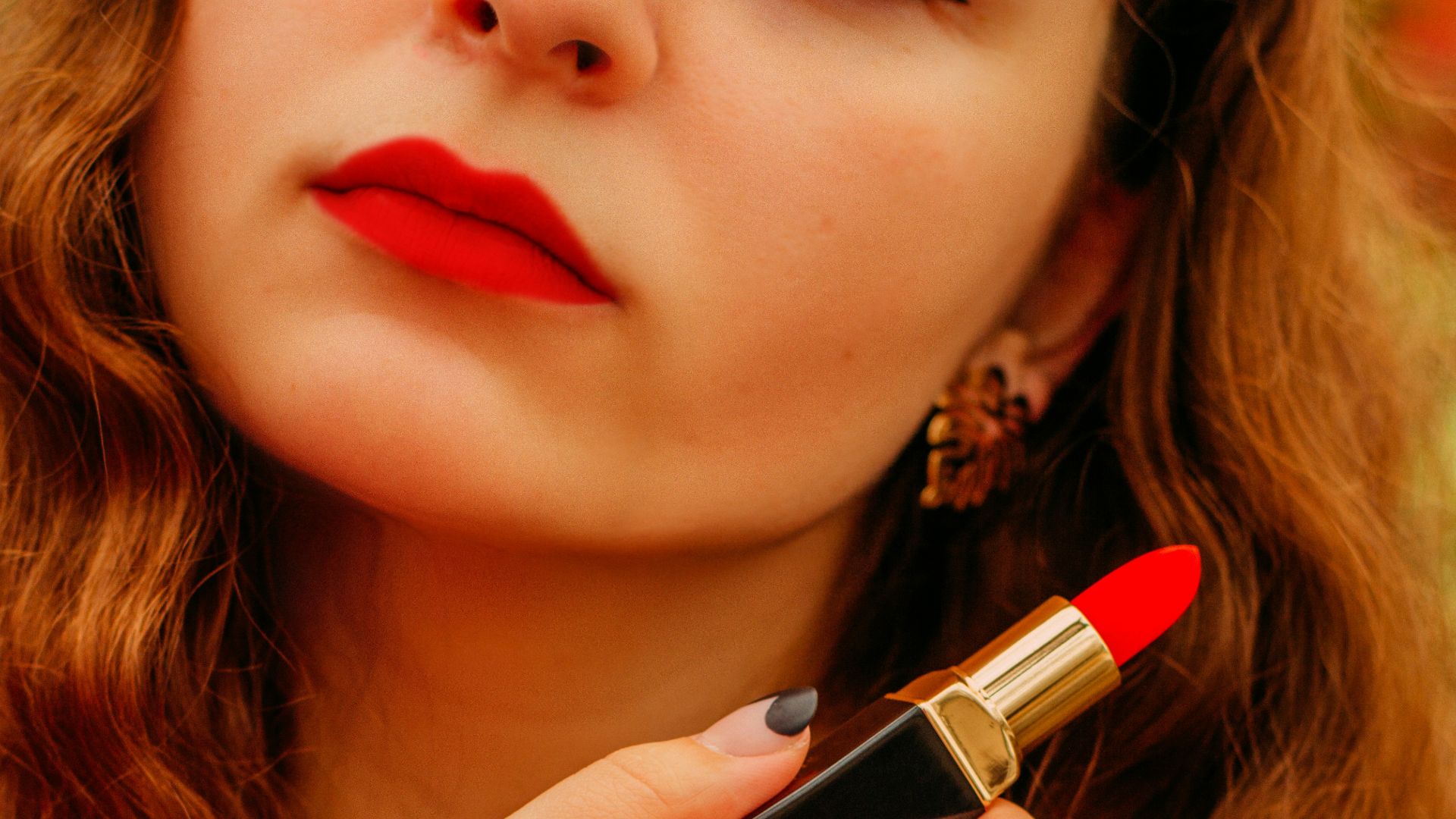 woman in pink shirt holding lipstick