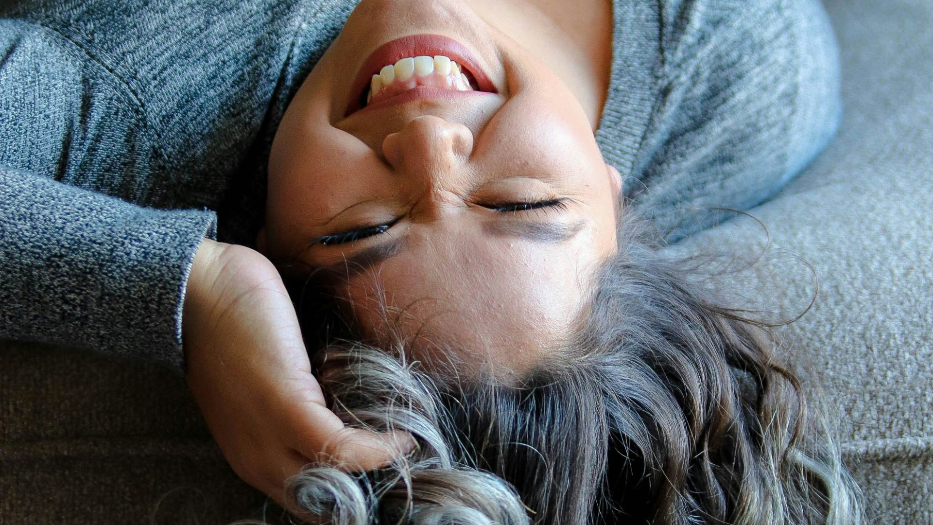 woman laying on couch near throw pillow
