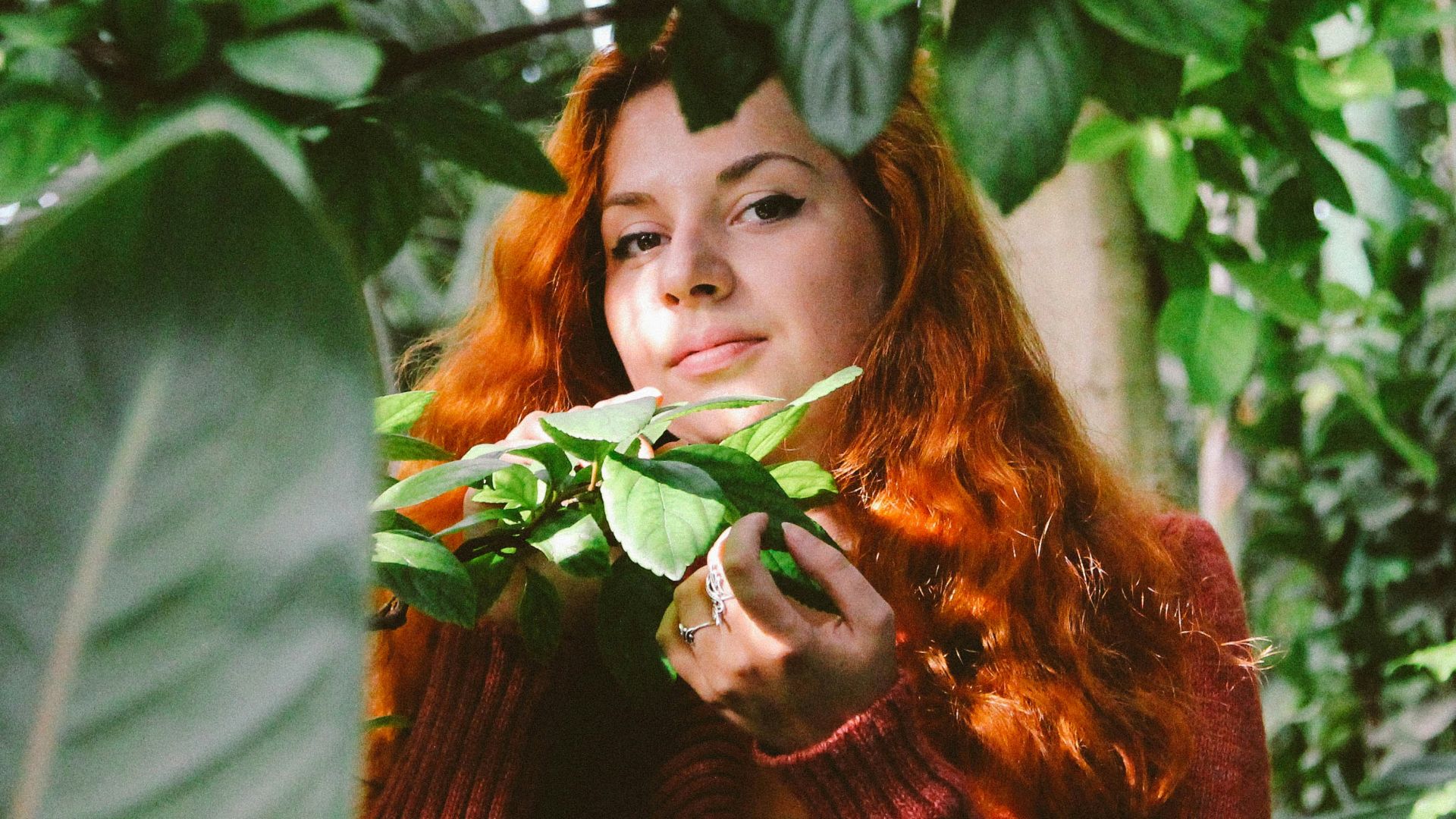 a woman with red hair is holding a plant