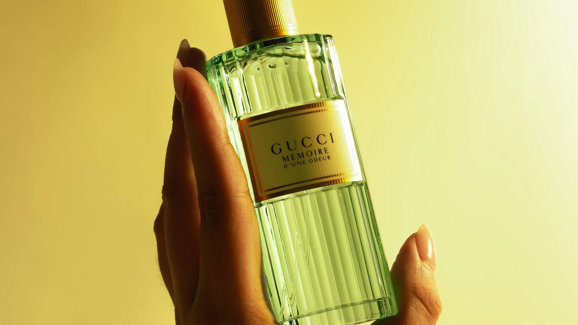 a hand holding a green bottle of perfume