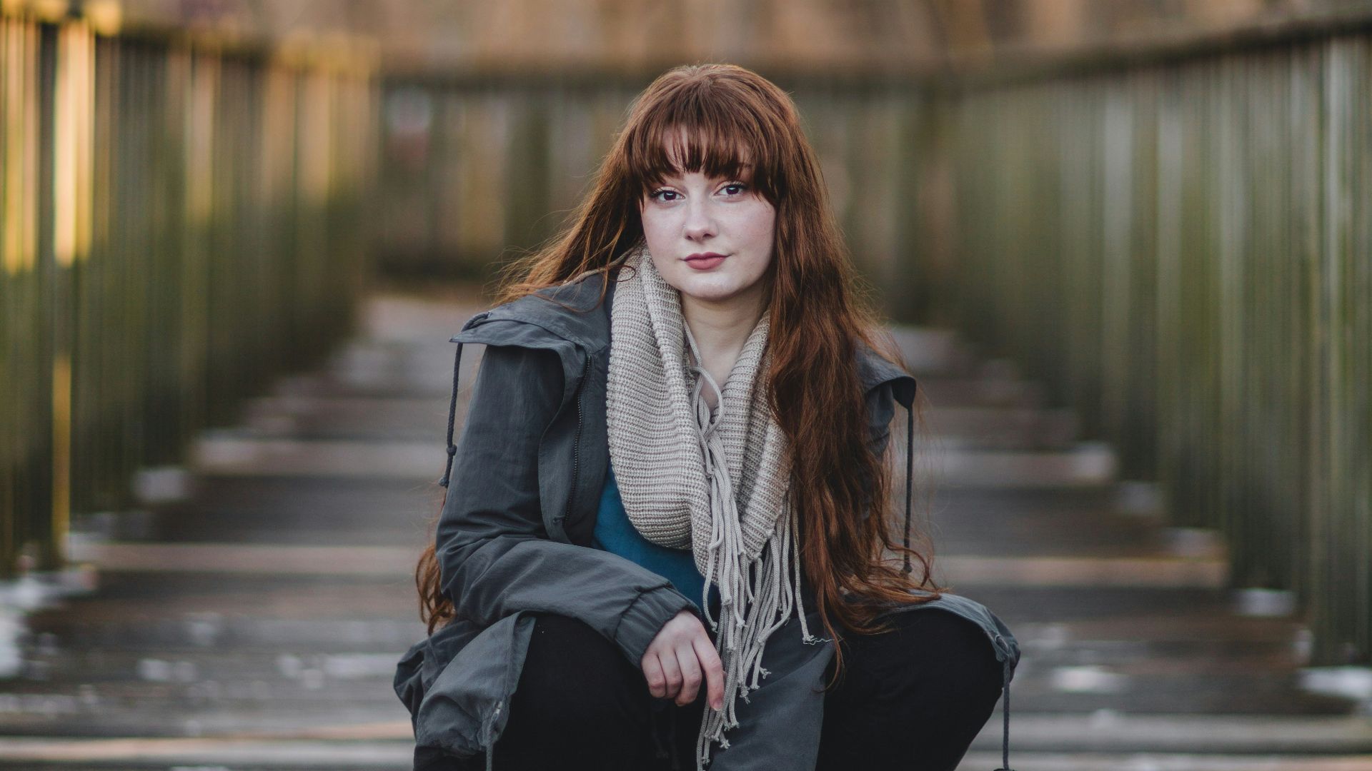 woman sitting on wooden bridge