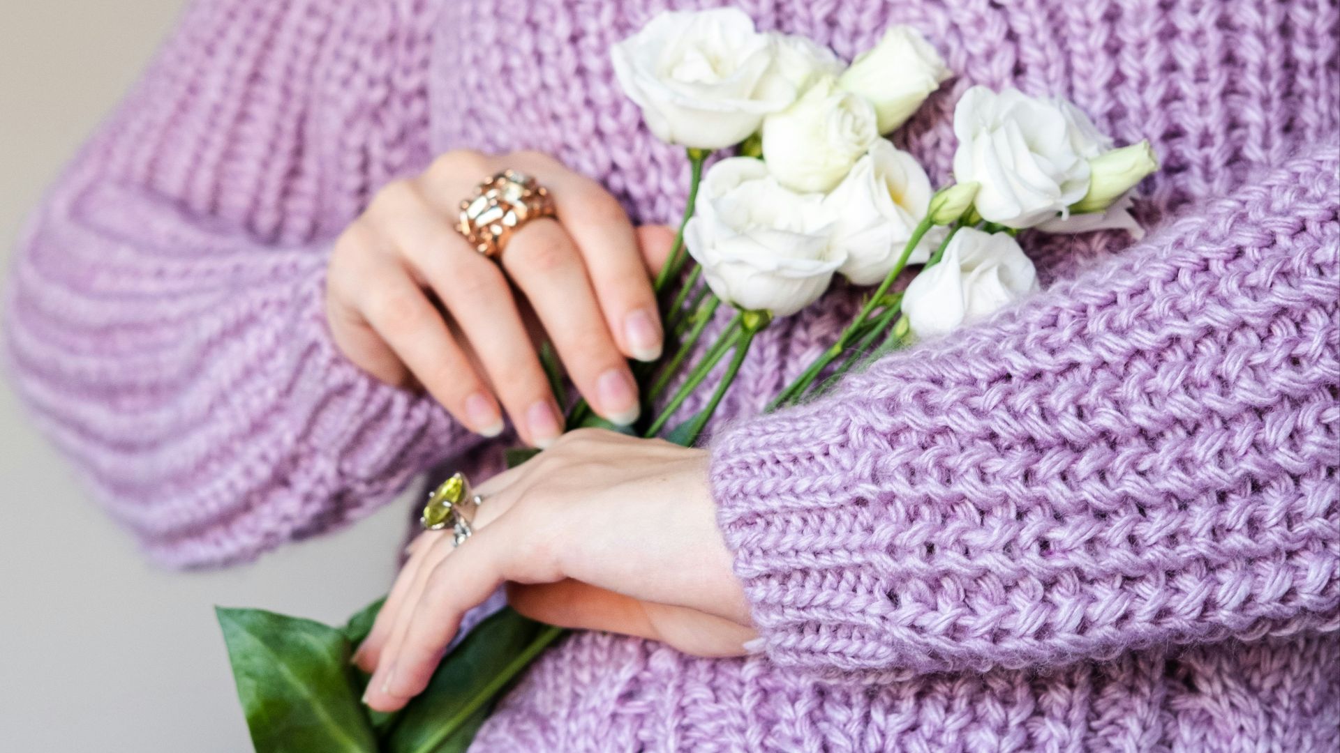 a woman in a purple sweater holding a bouquet of flowers