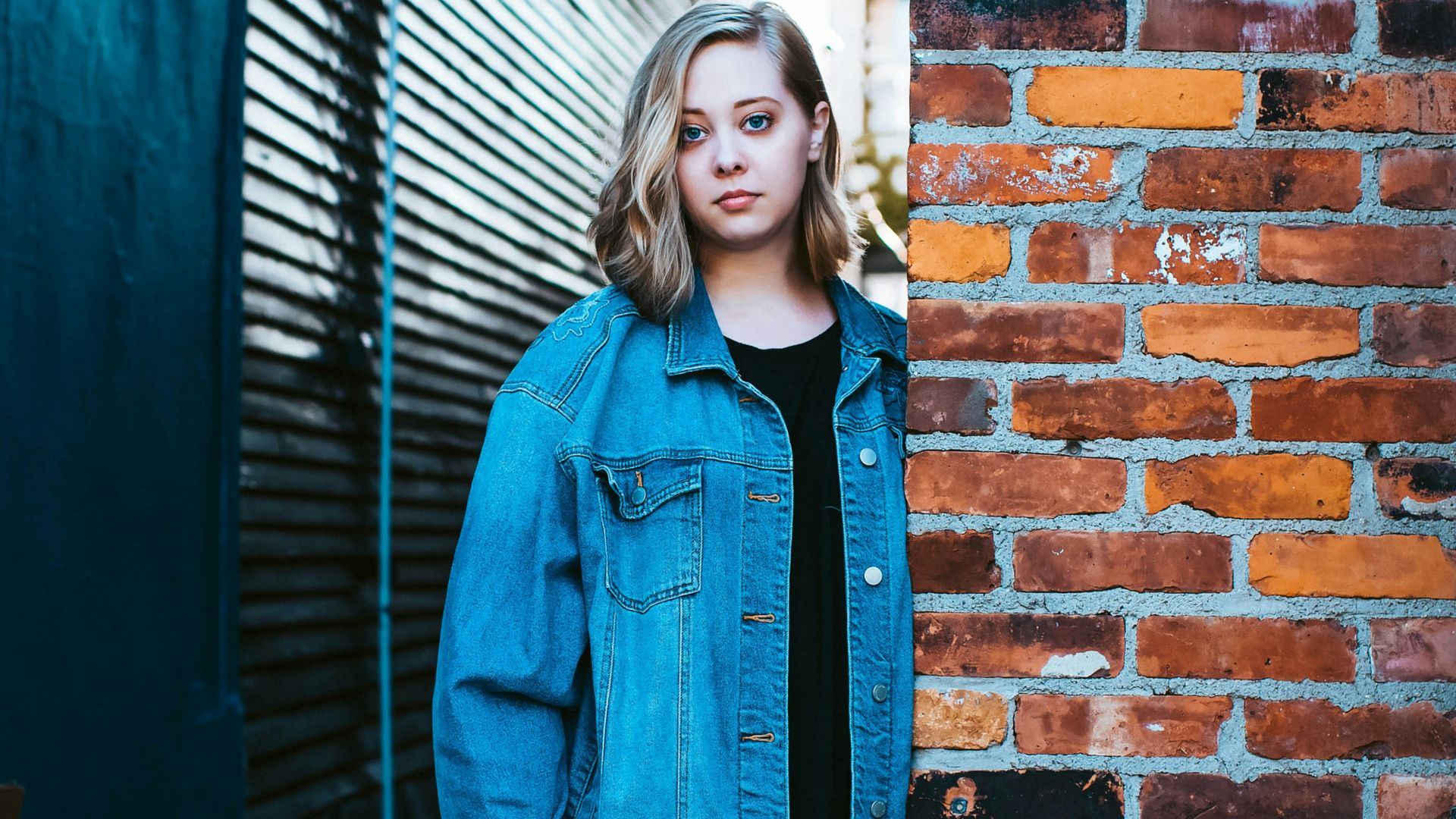 woman leaning on brown brick wall
