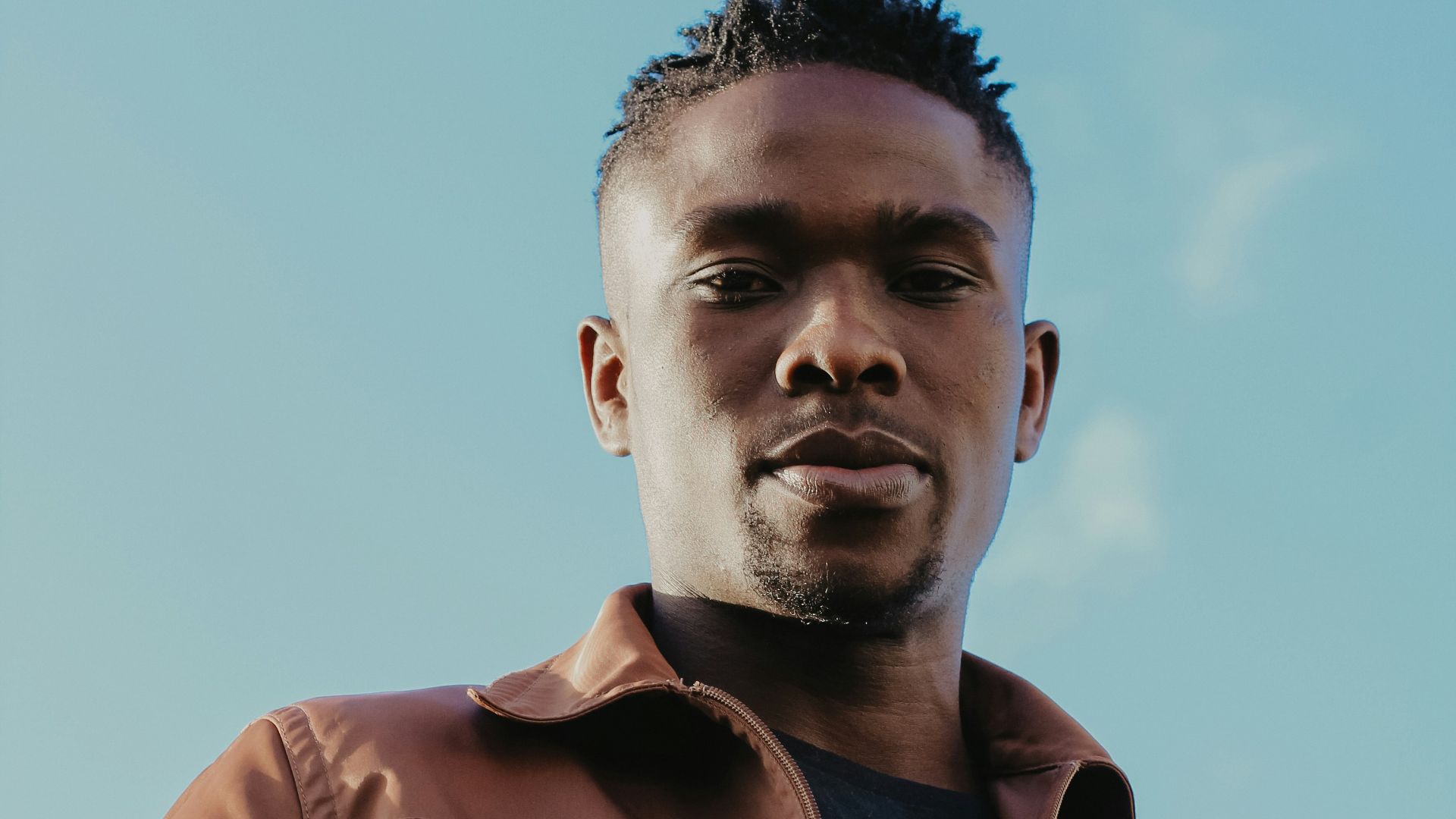 a man wearing a brown jacket and a black shirt