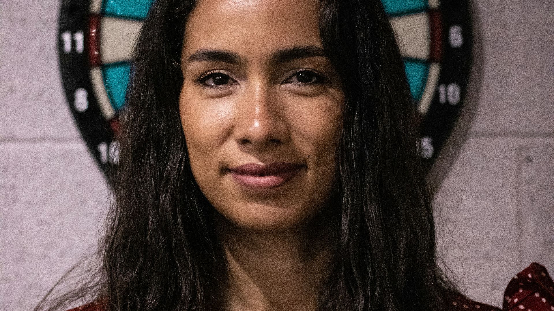 a woman standing in front of a dart board