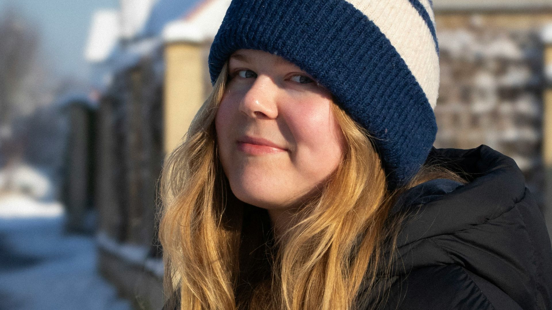 a woman standing in the snow in front of a house