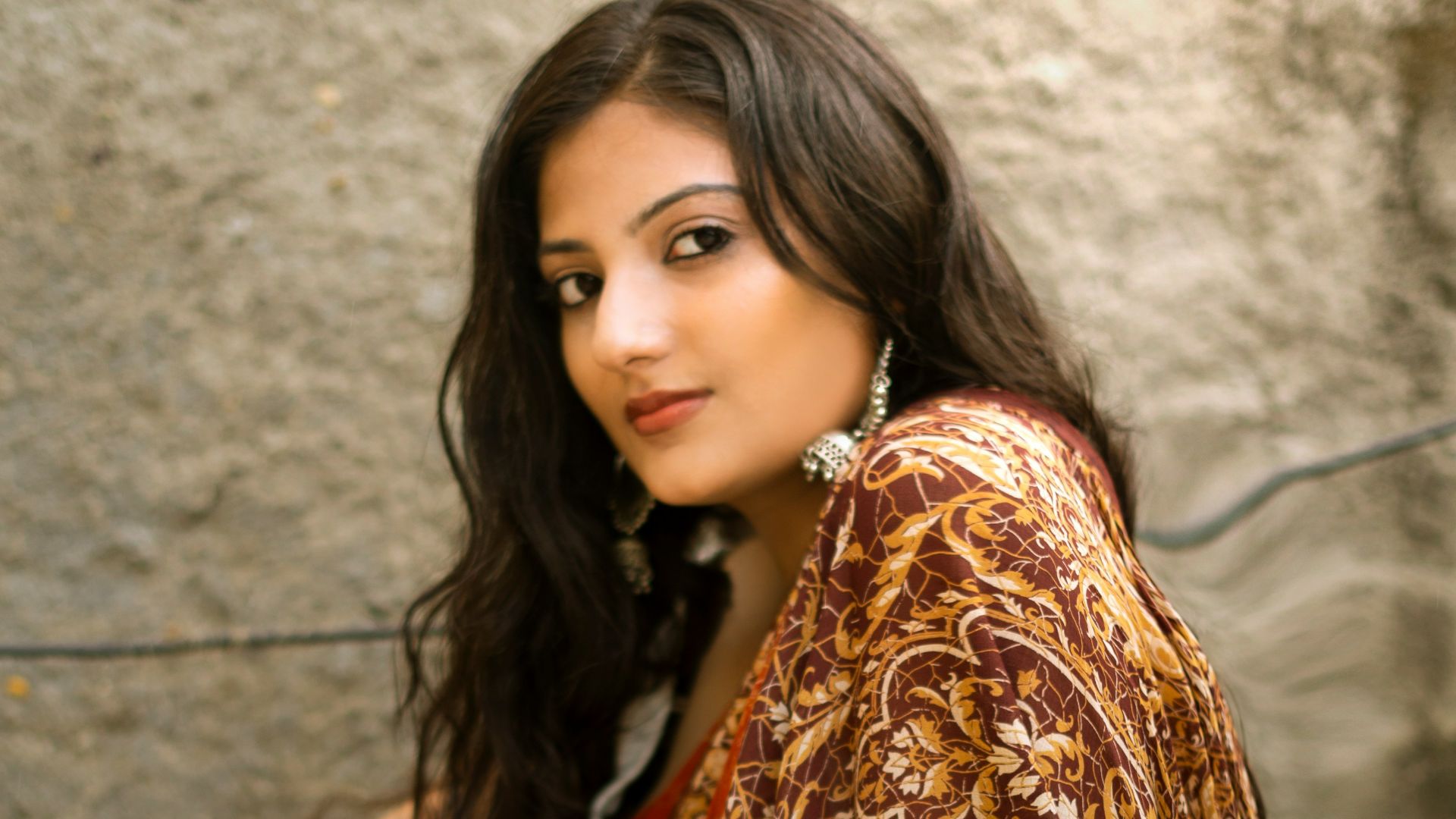 woman in red and gold sari dress sitting on gray concrete stairs
