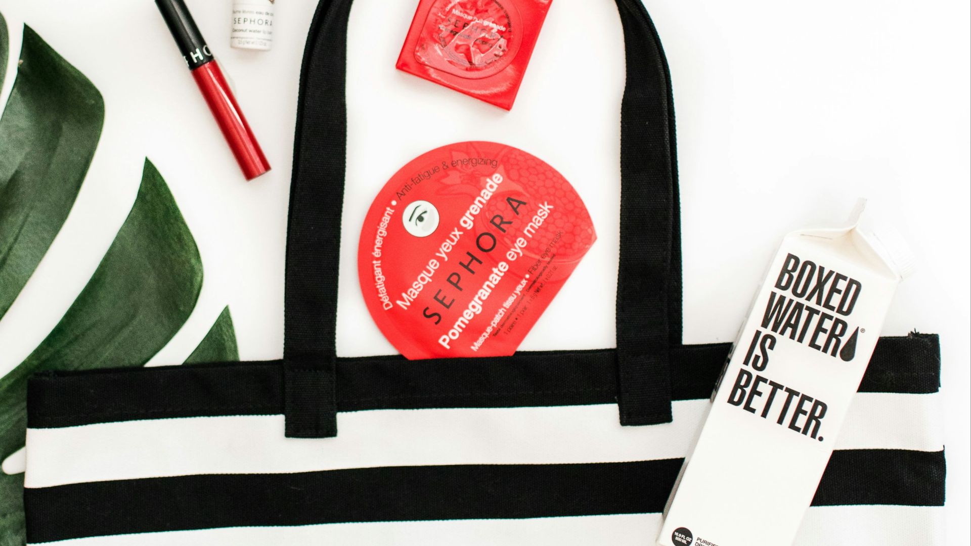 A black and white striped handbag with Sephora and Boxed Water products displayed next to it