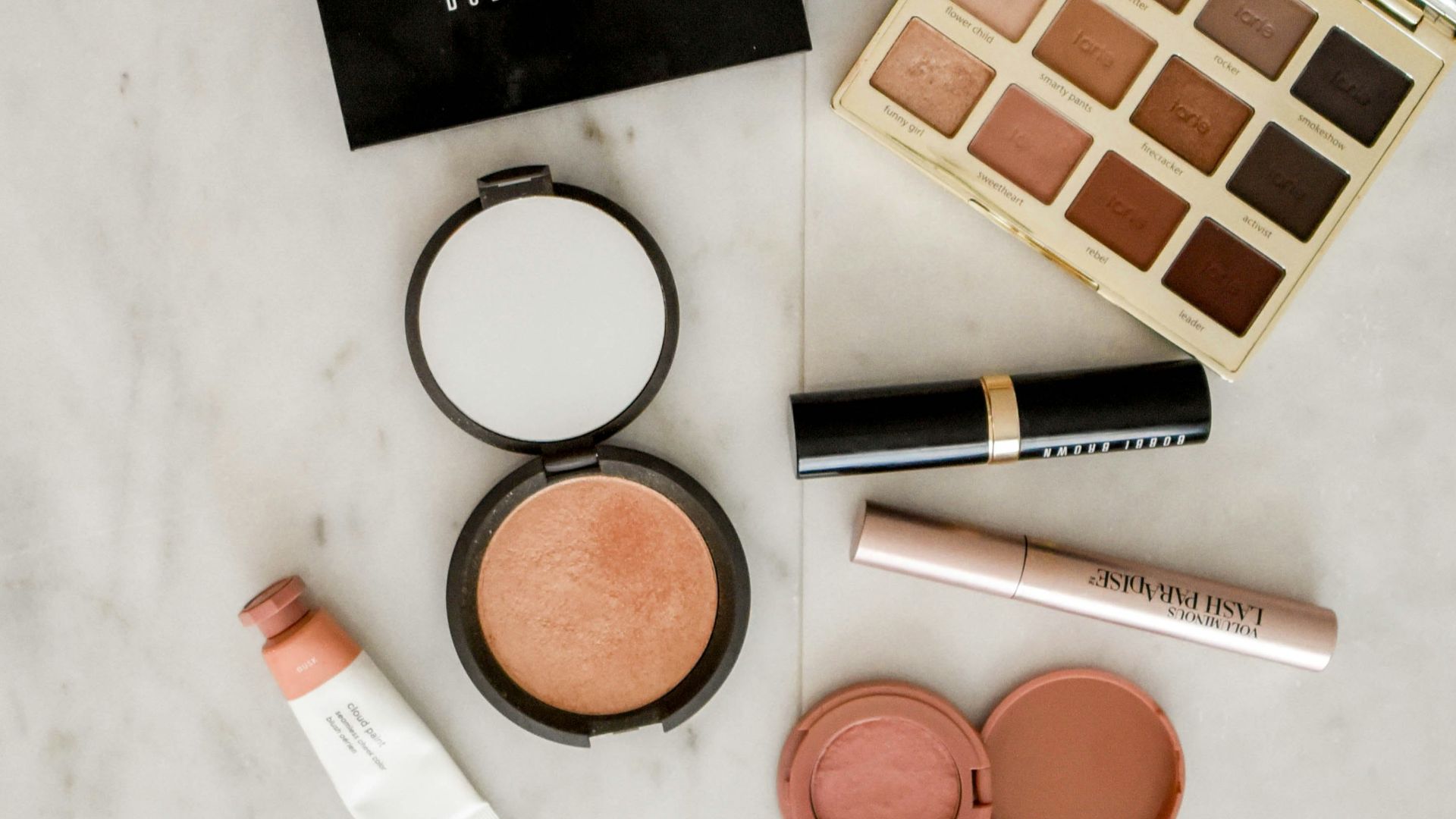 photo of assorted makeup products on gray surface