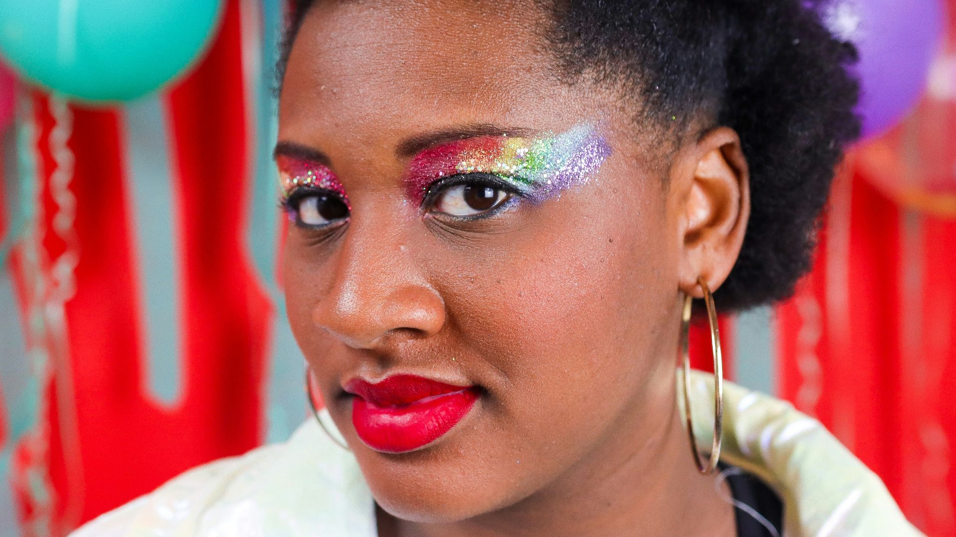 Woman with colorful eyeshadow and red lips smiles