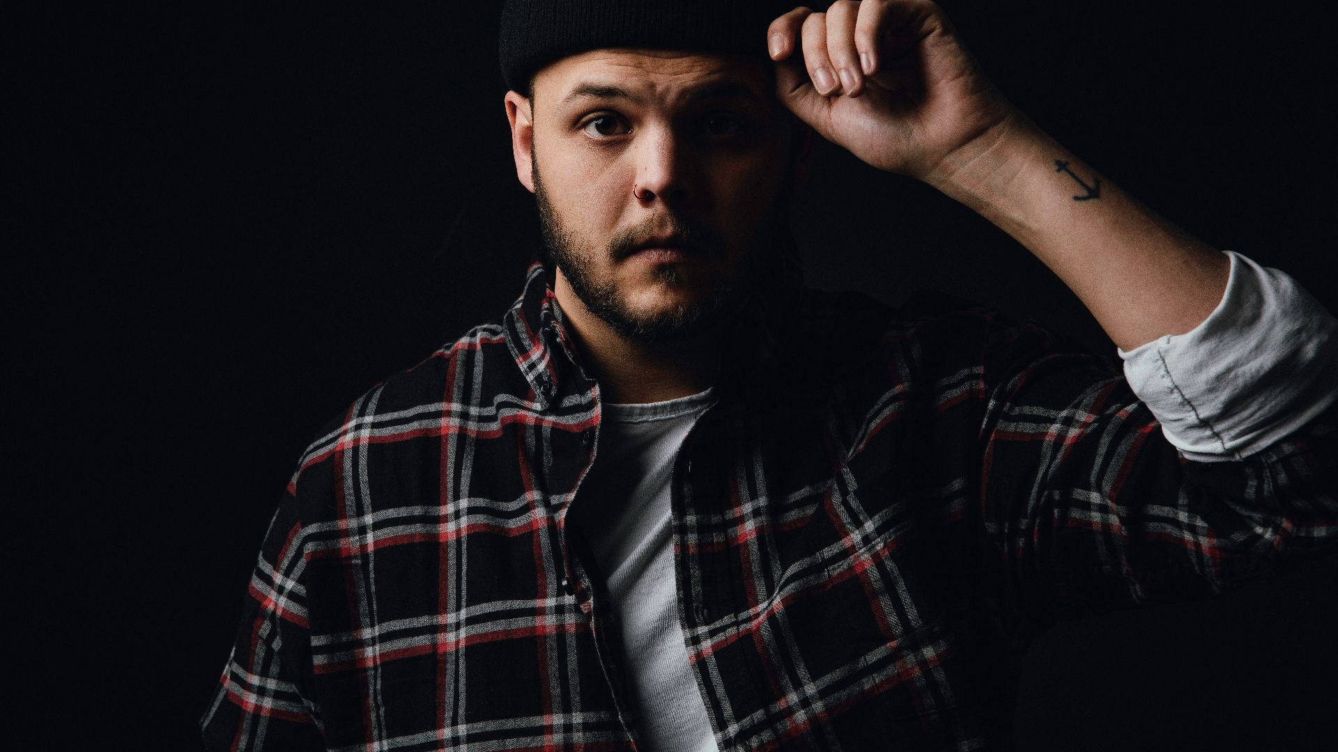 man in black and red plaid dress shirt wearing black cap