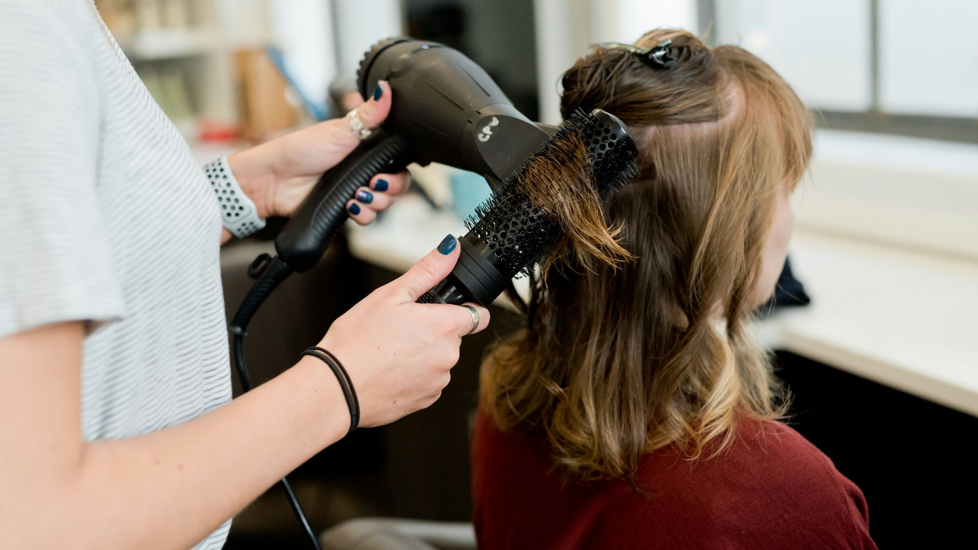 woman in red long sleeve shirt holding hair blower
