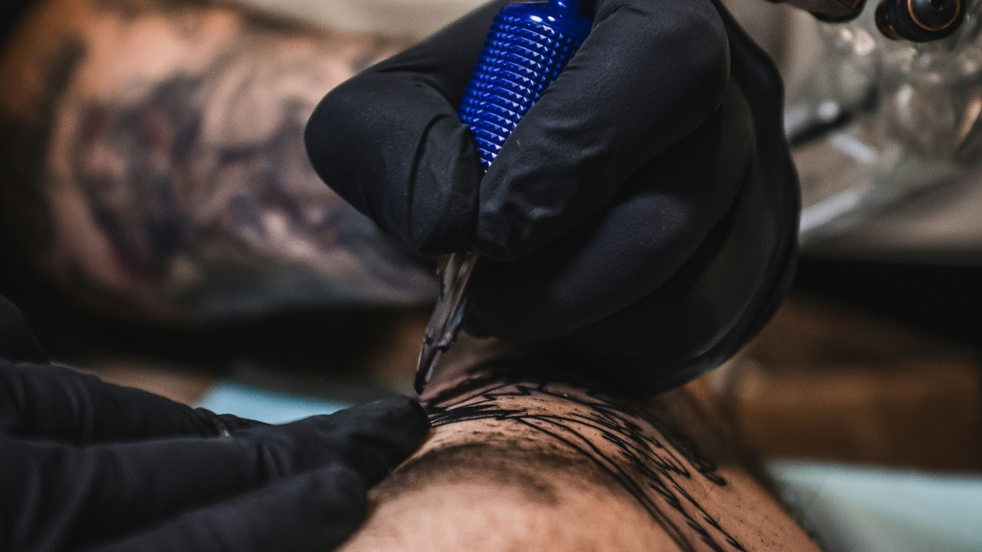 person holding blue and brown tattoo machine