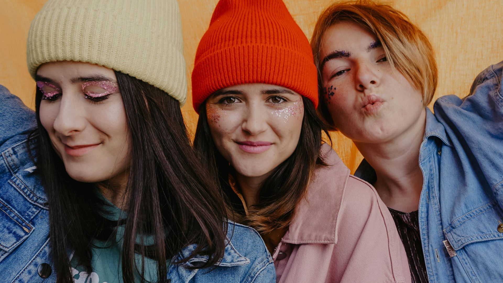 woman in blue denim jacket beside woman in red knit cap