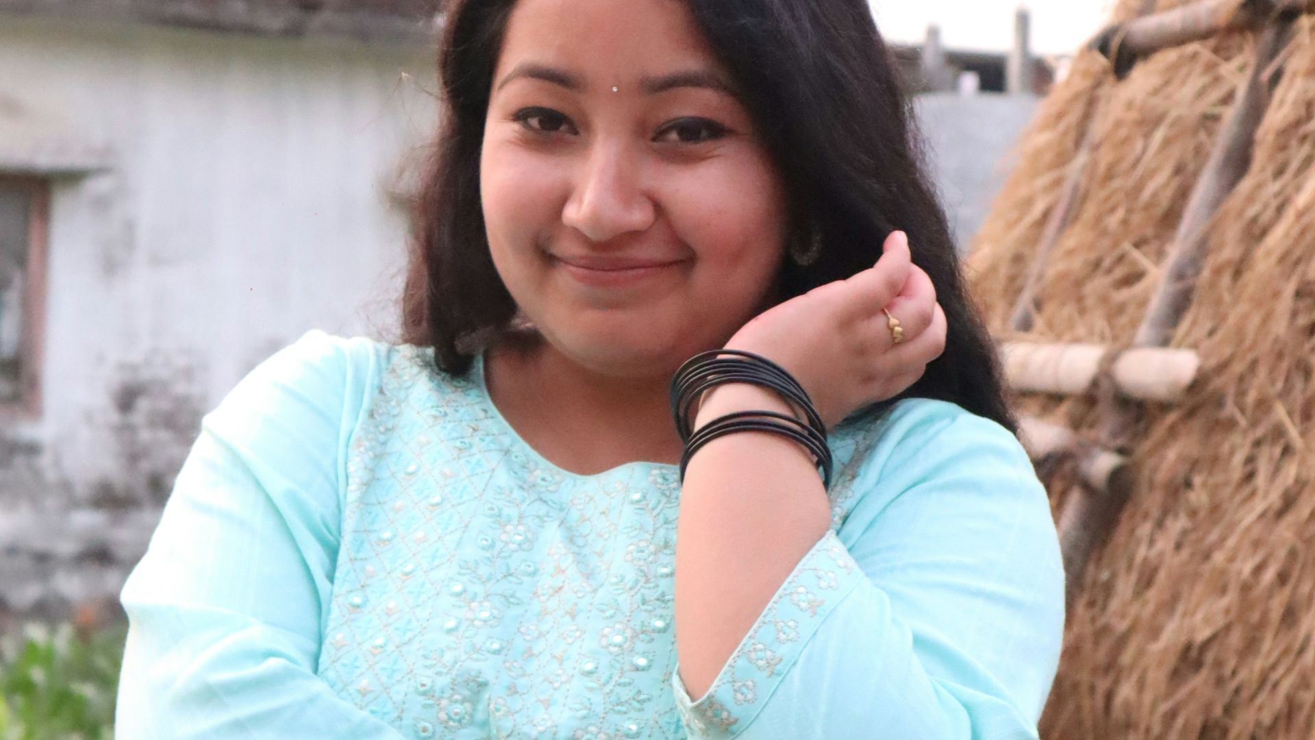 a woman standing in front of a straw hut