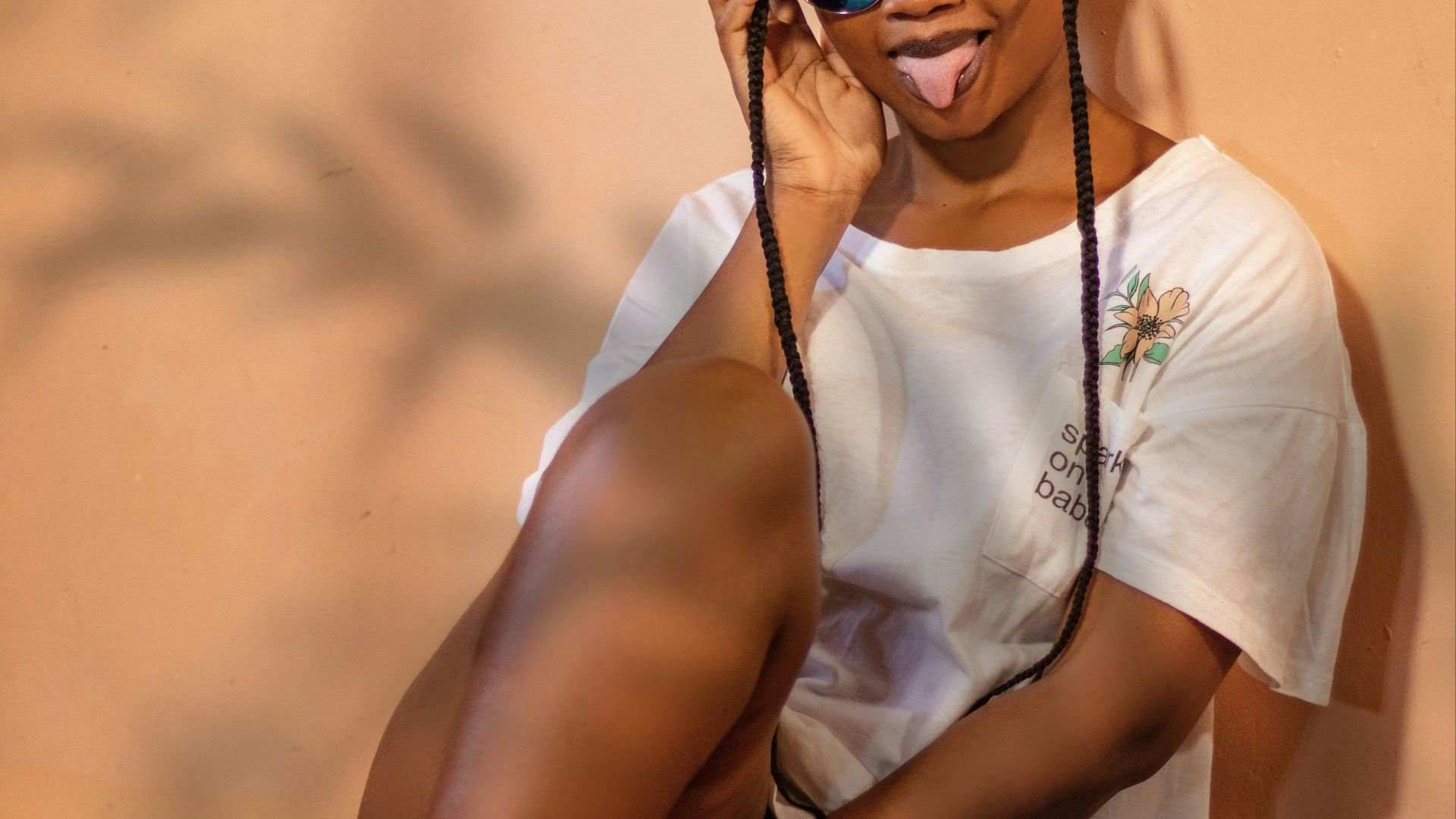 a woman wearing sunglasses and a white shirt sitting on the floor