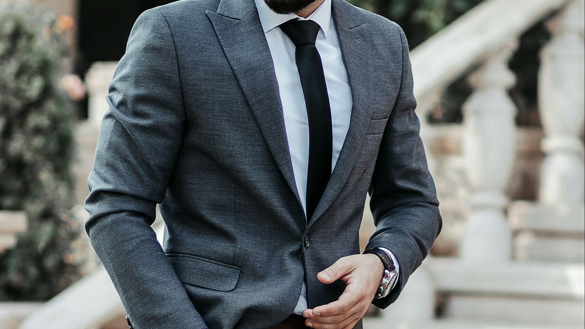man in gray suit jacket and black pants wearing black sunglasses standing on gray concrete stairs