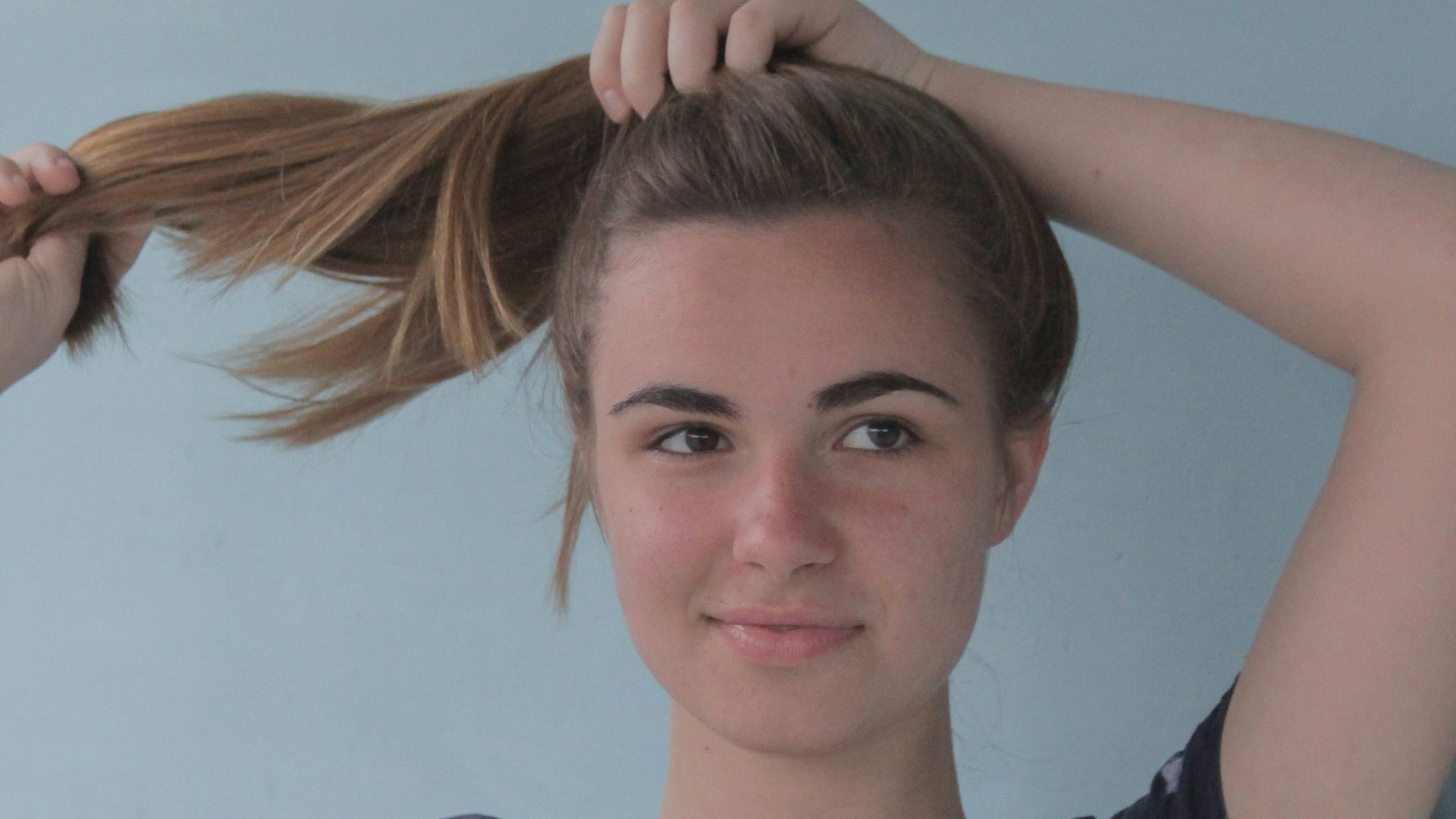 smiling woman standing and fixing her hair