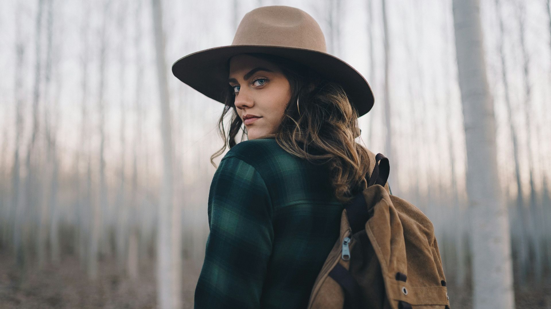 a woman wearing a hat in a forest