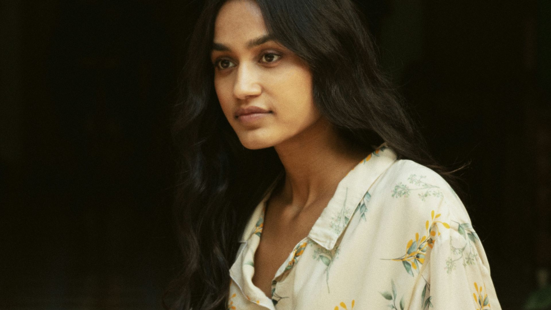 A woman wearing a floral print shirt outdoors.