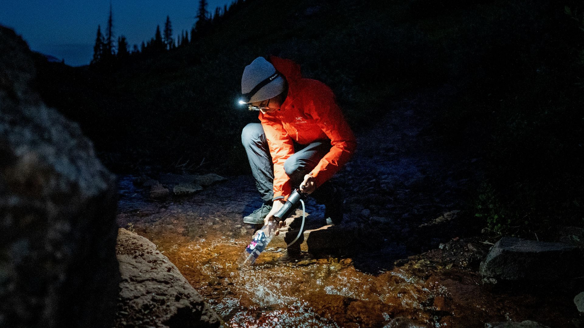 man in red shirt and white pants standing on rocky hill during daytime