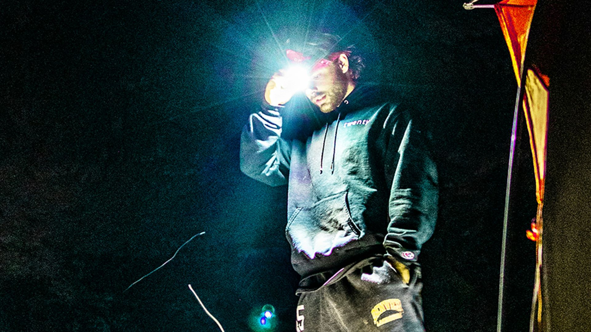 man in black jacket and blue denim jeans standing on orange tent