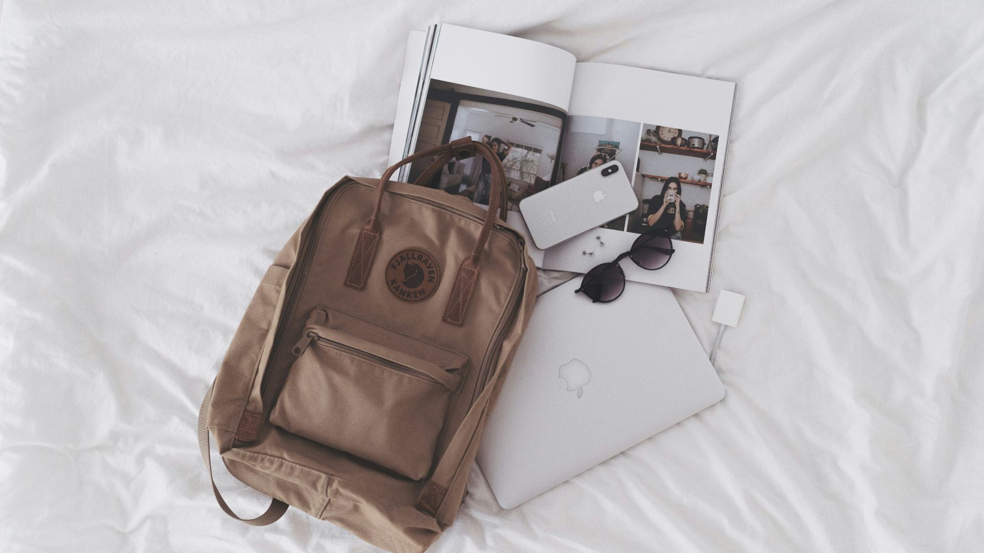 silver ipad beside brown leather handbag