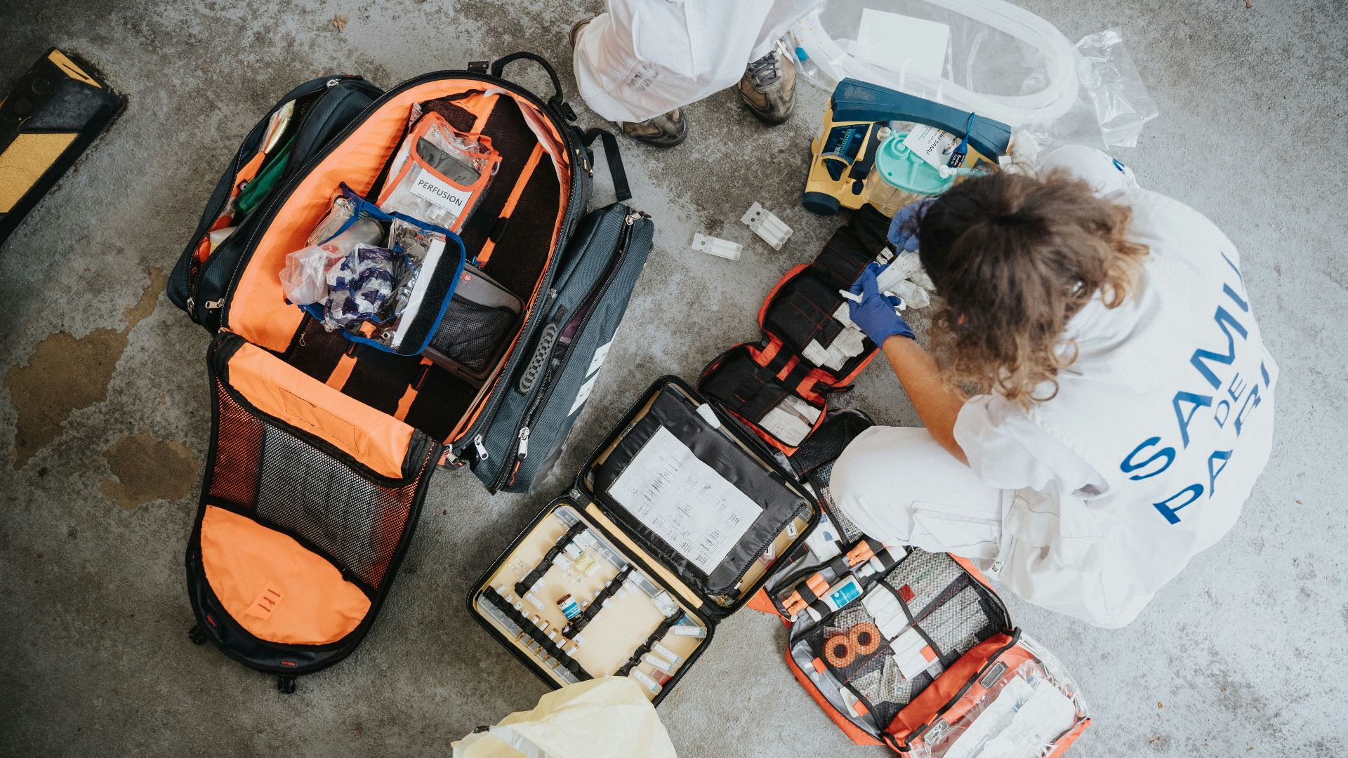 boy in white shirt sitting on orange and black backpack
