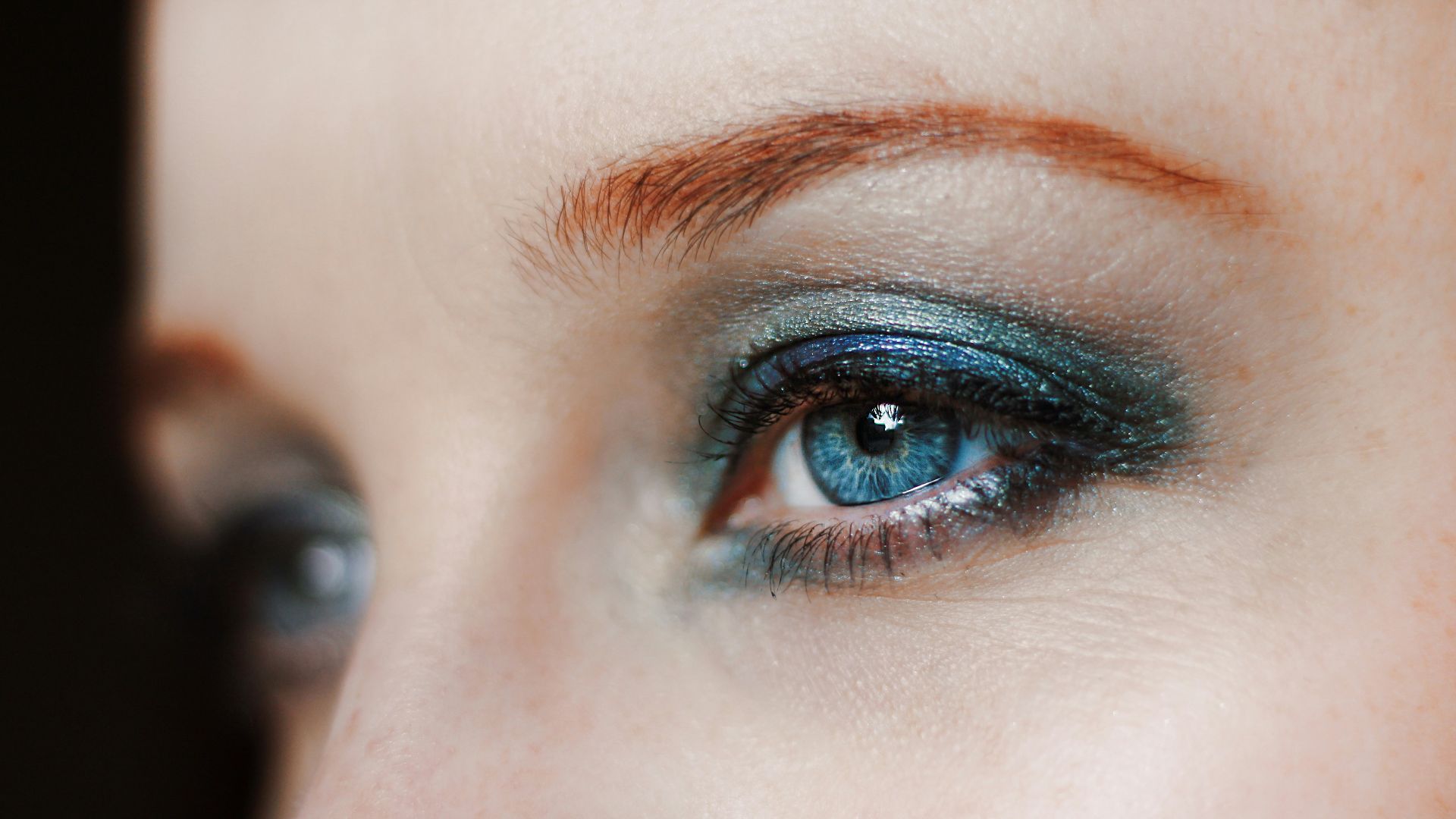 a close up of a woman's eye with blue eyeshadow