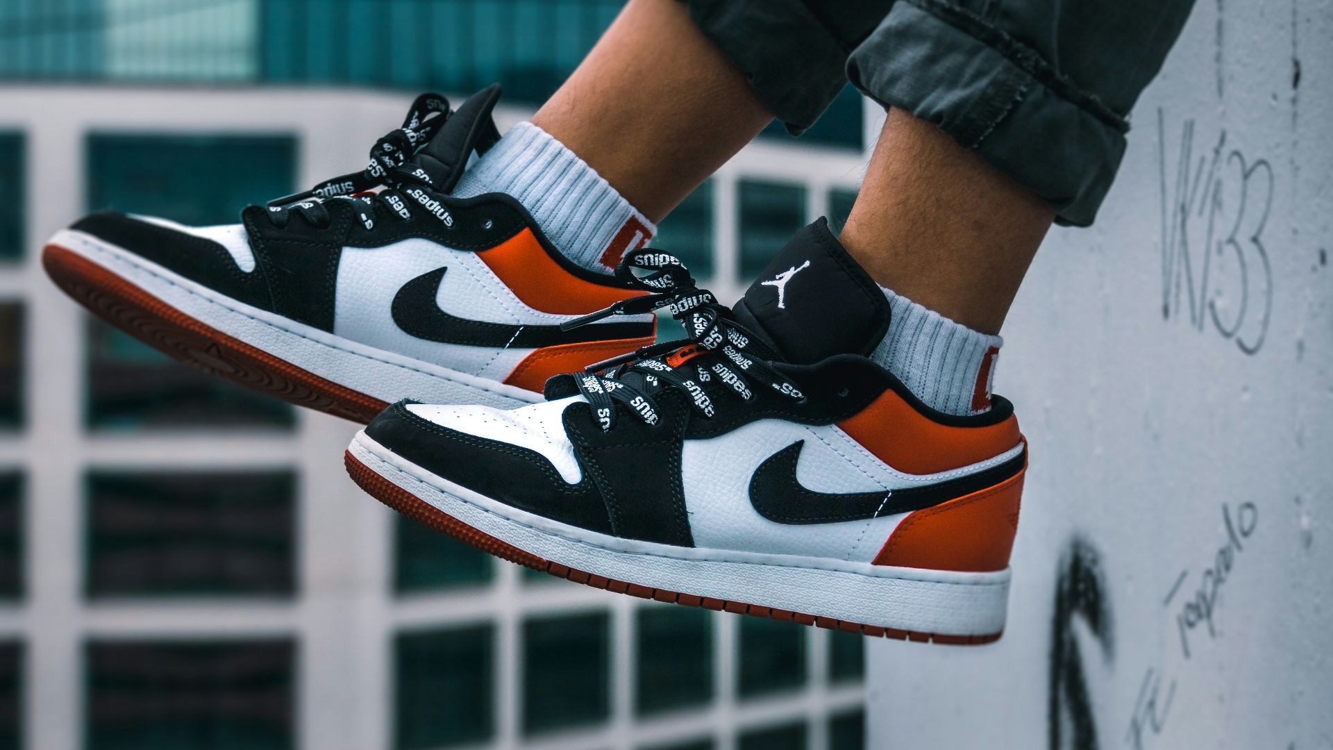 man sitting on the ledge of a building wearing Air Jordan 1 low-top shoes
