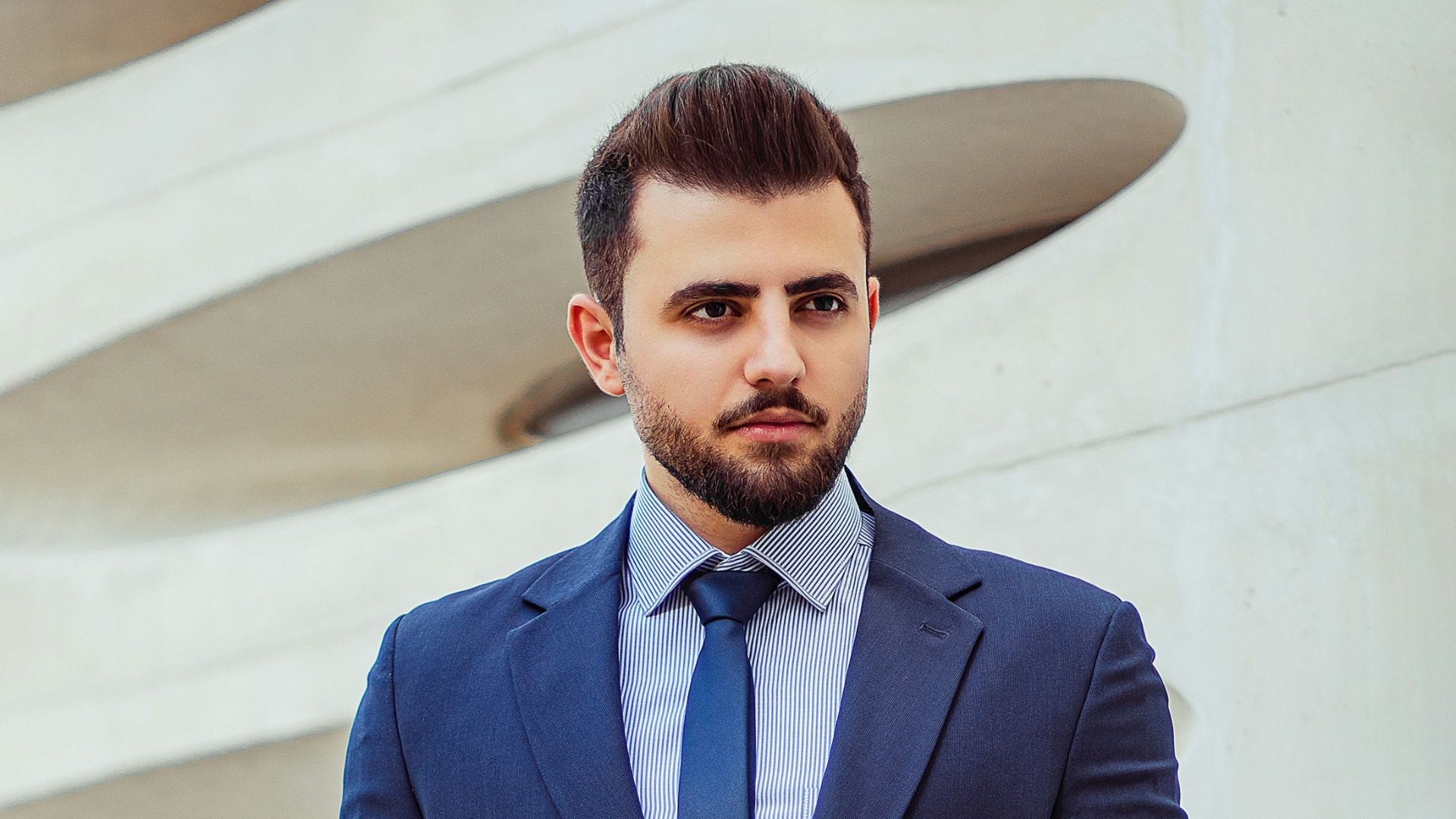 man in black suit jacket holding brown leather bag
