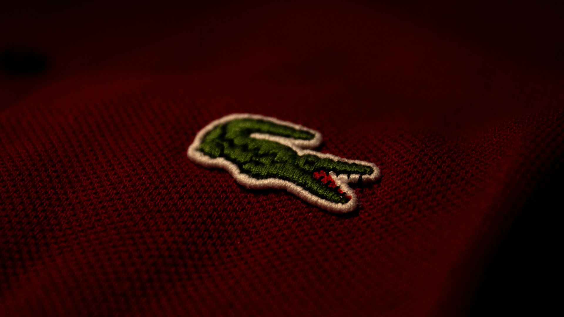 a close up of a red polo shirt with a green alligator embroidered on it