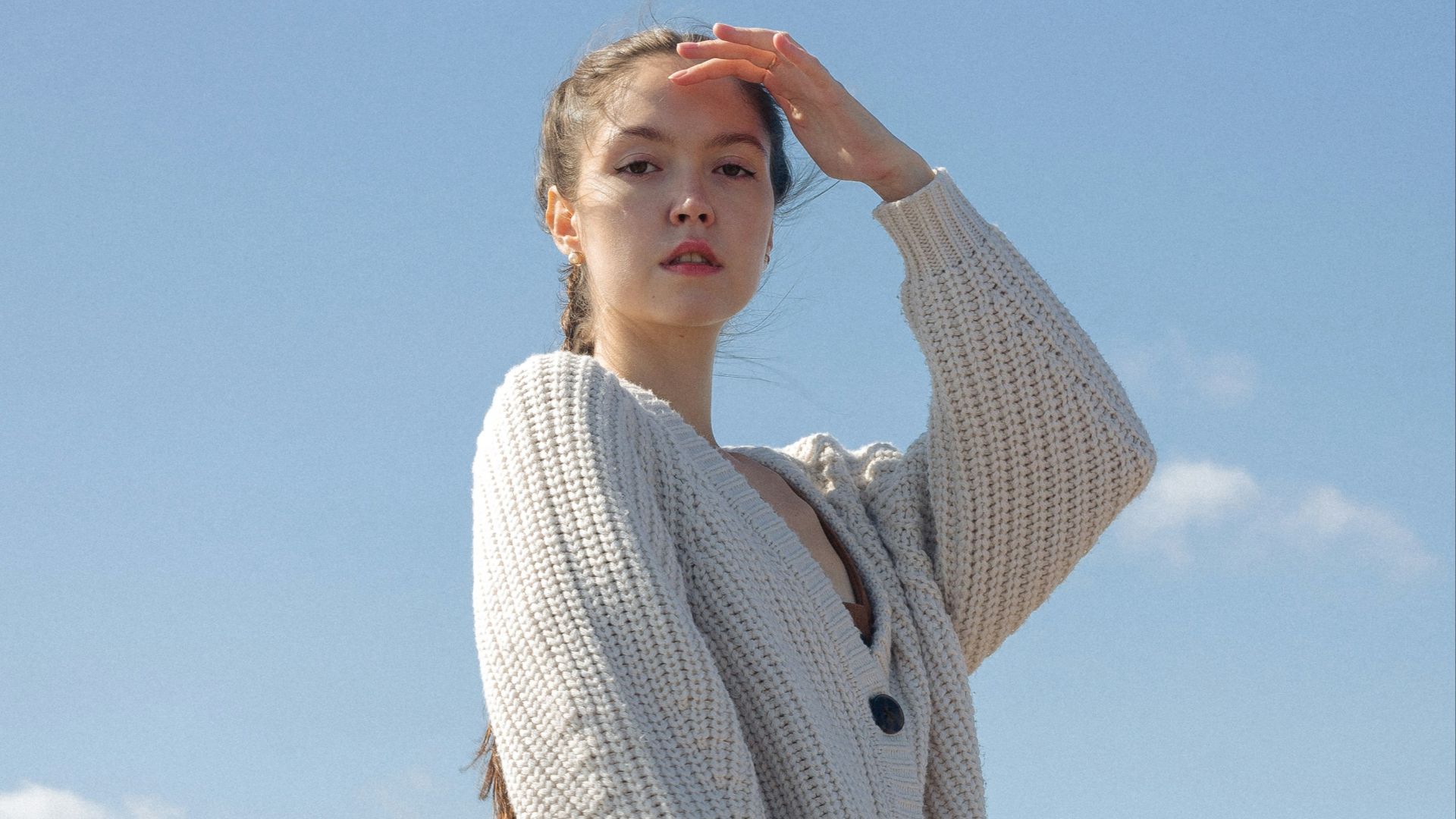 woman in white knit sweater and brown shorts standing under blue sky during daytime