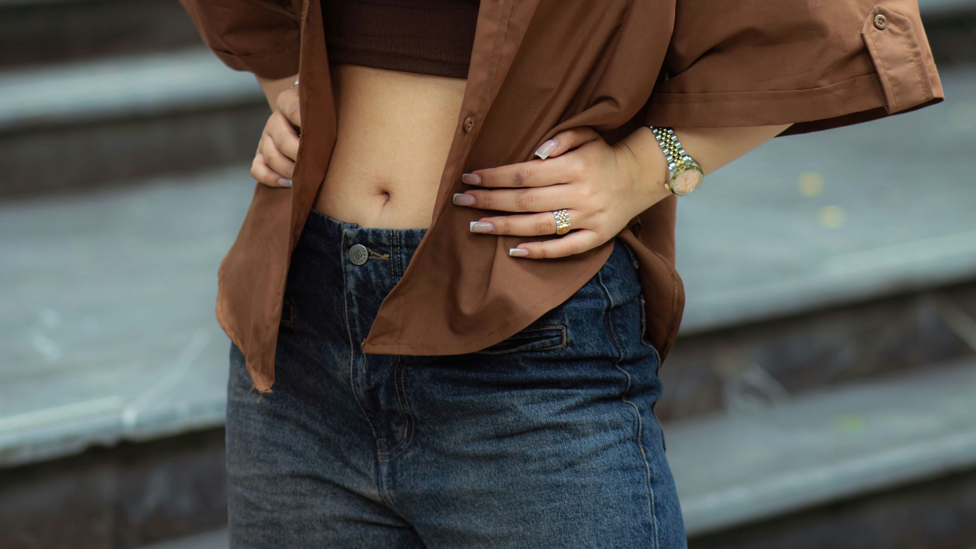 A young woman in a brown shirt and jeans.