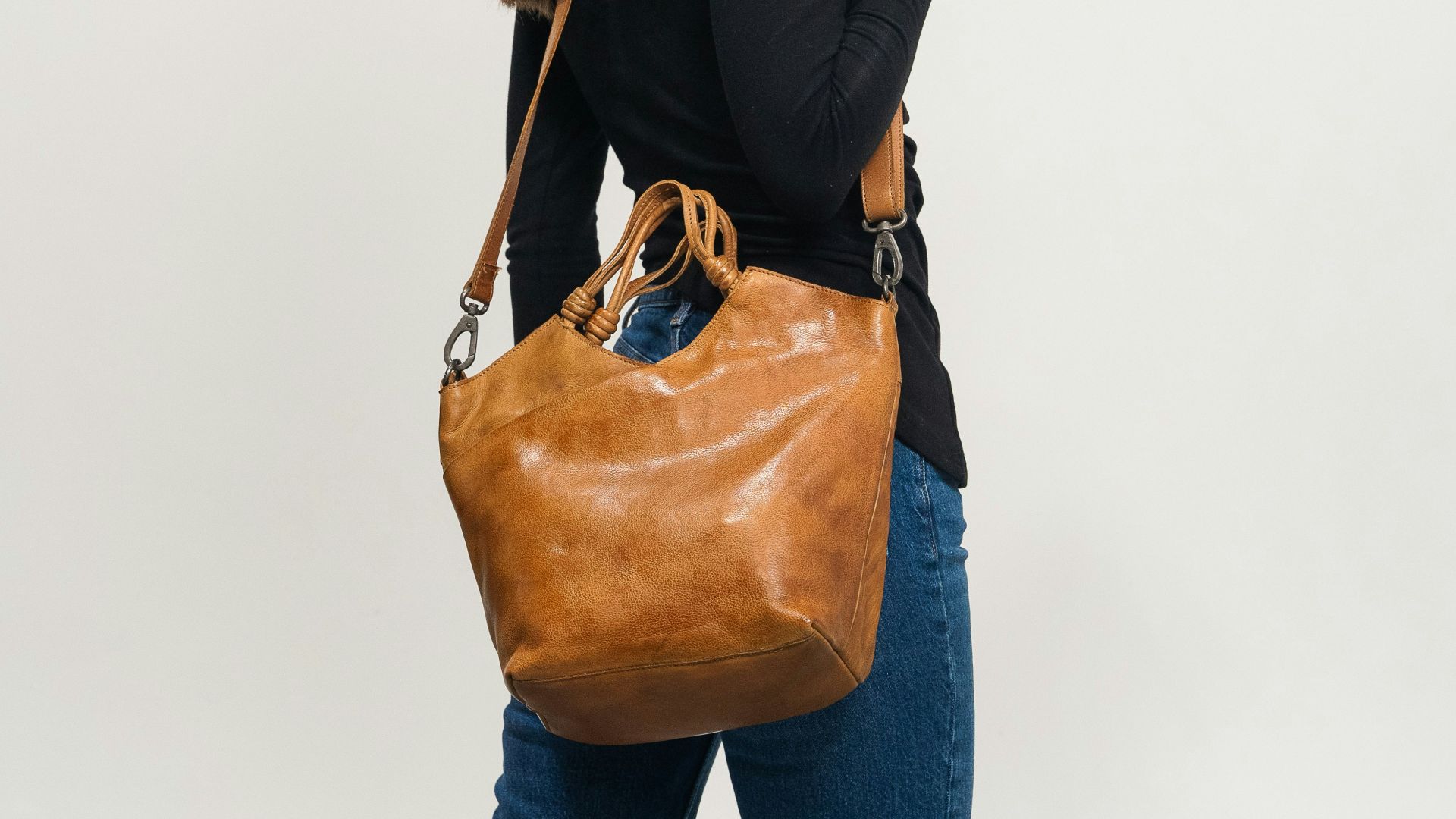 Woman in black shirt carrying a brown leather handbag