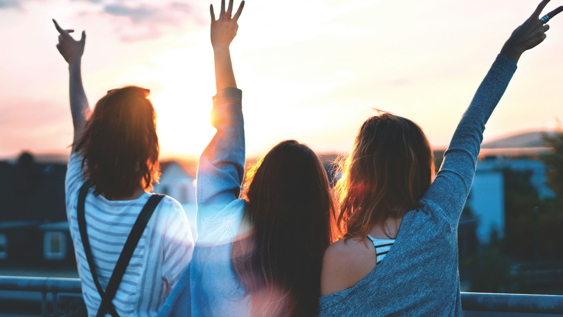 photo of three women lifting there hands \