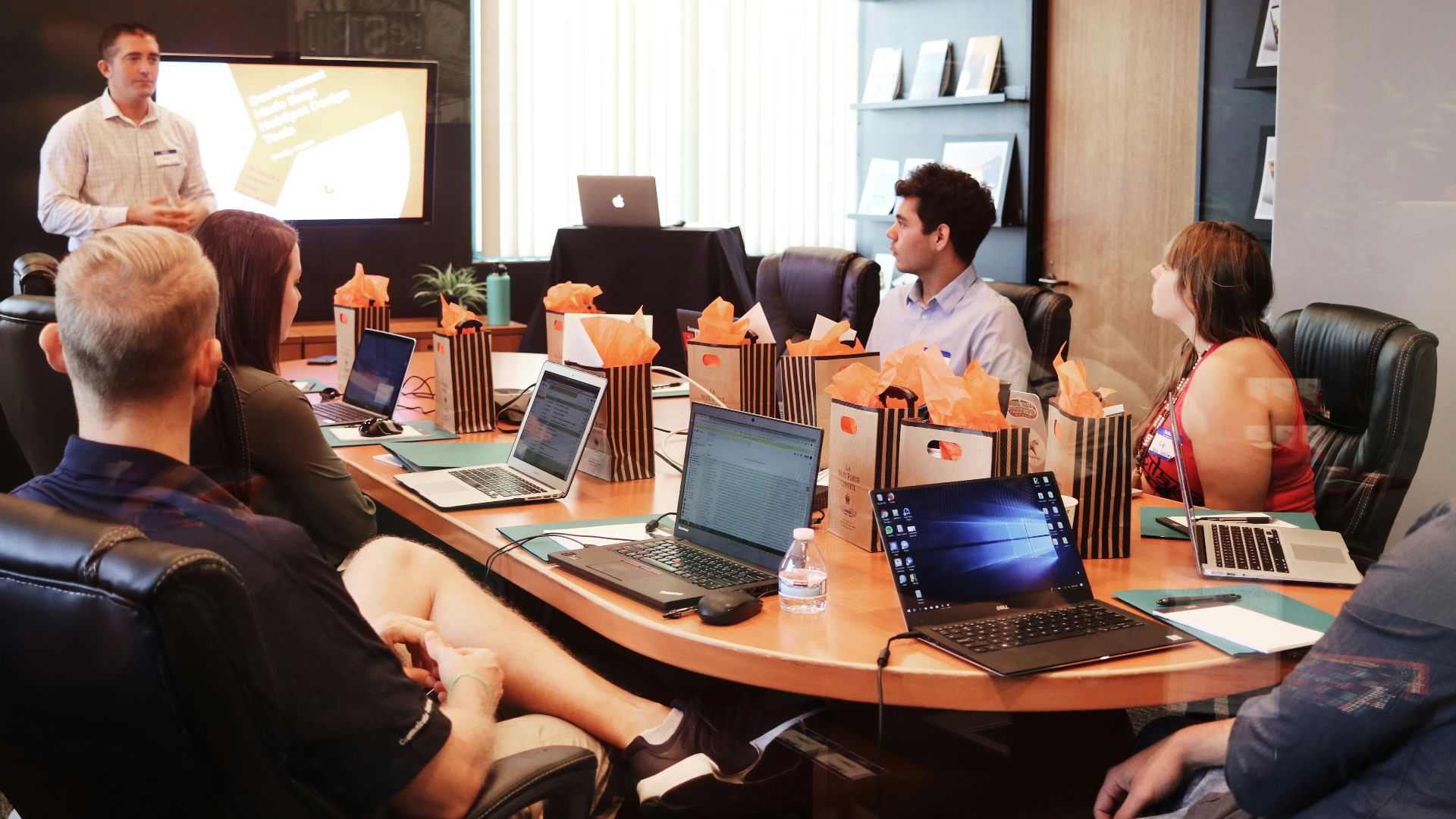 man standing in front of people sitting beside table with laptop computers